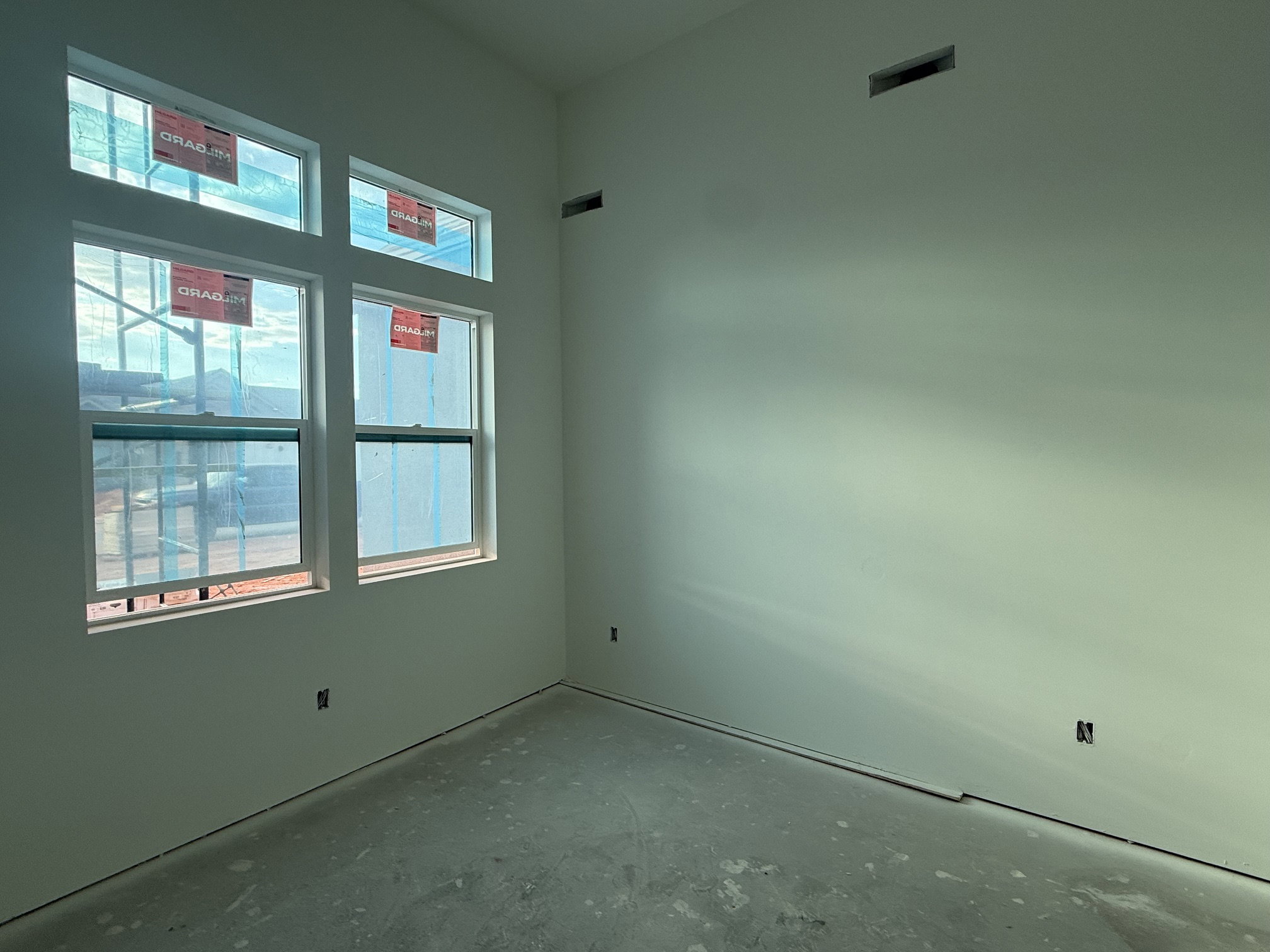 Newly constructed interior space with high ceilings and multiple windows providing natural light
