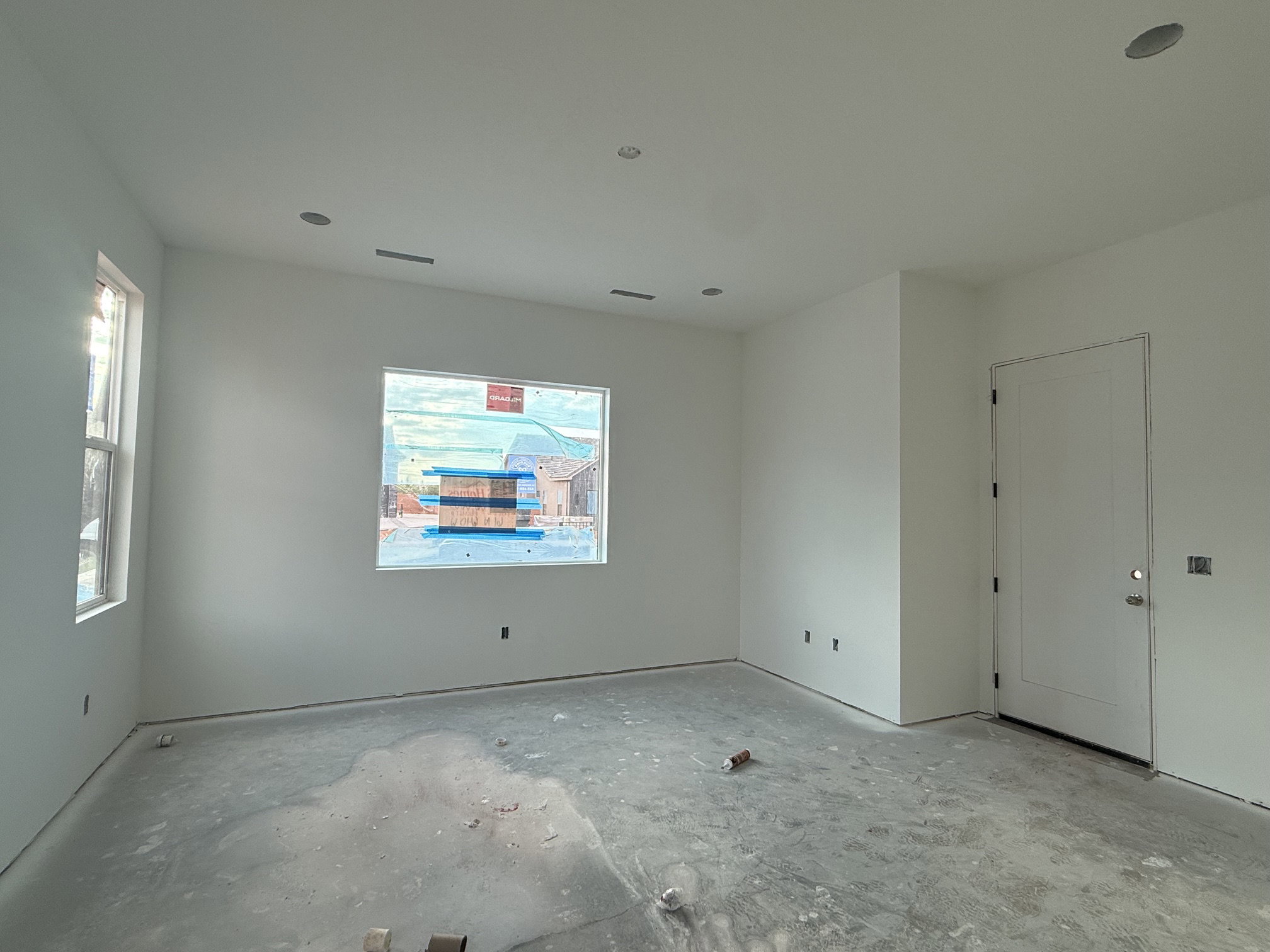 Spacious interior room featuring white walls, a large window, a second vertical window, and recessed ceiling lighting