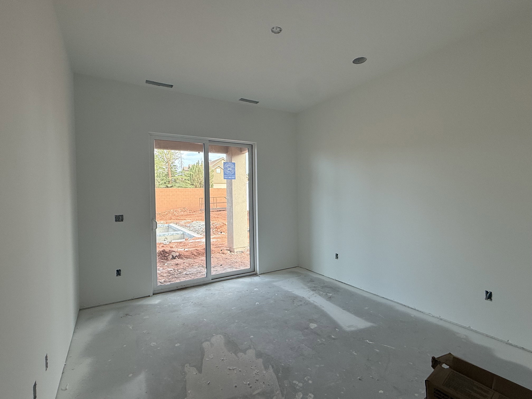 Sliding glass door opening to an exterior area with red earth, featuring white walls, recessed ceiling lighting, and overhead vents