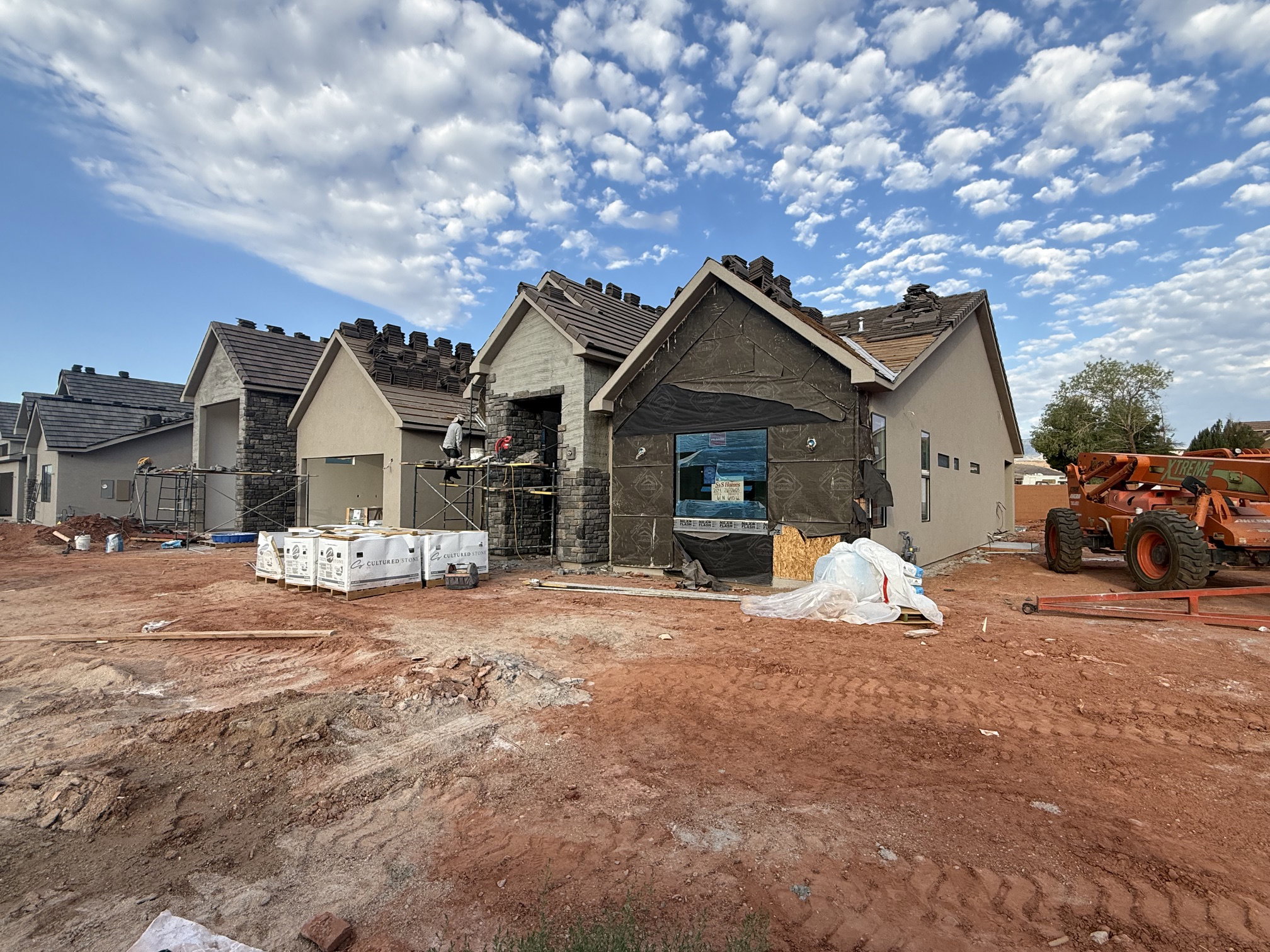 Newly constructed residential property featuring stone veneer accents, stucco siding, and a tile roof