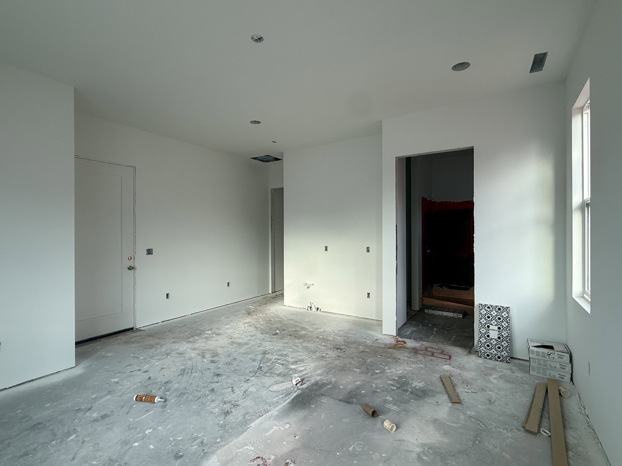 Spacious room with white painted walls, recessed lighting, and a visible window