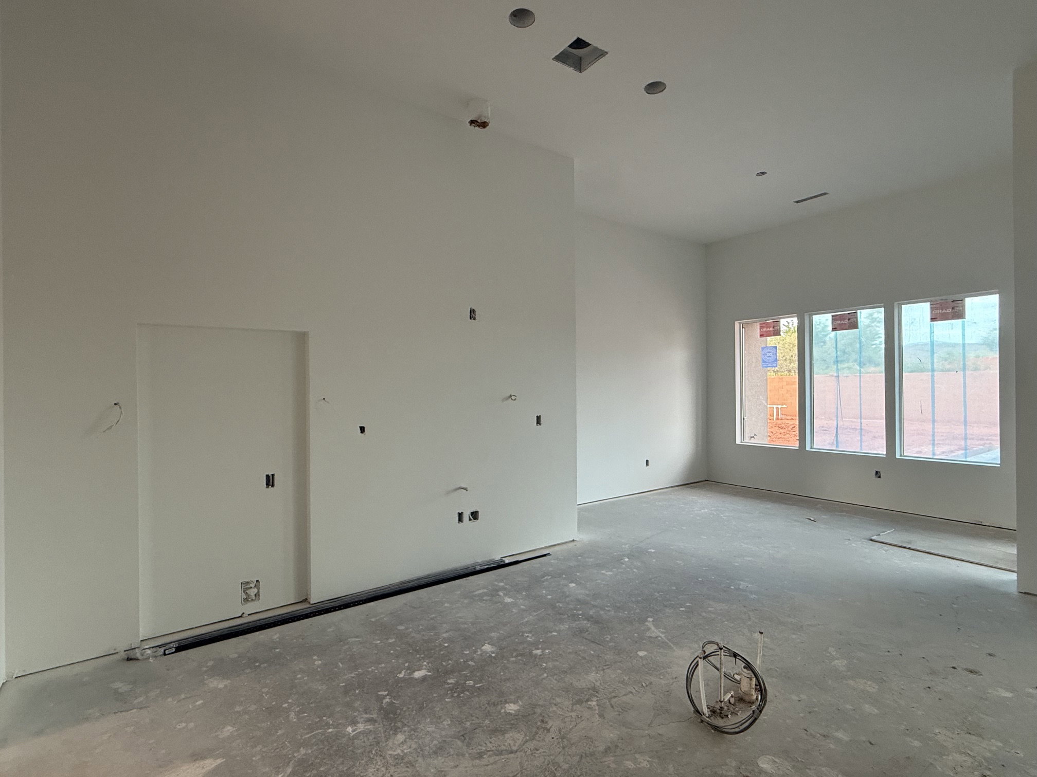 Spacious interior featuring high ceilings, three large windows, recessed lighting, and an open floor plan
