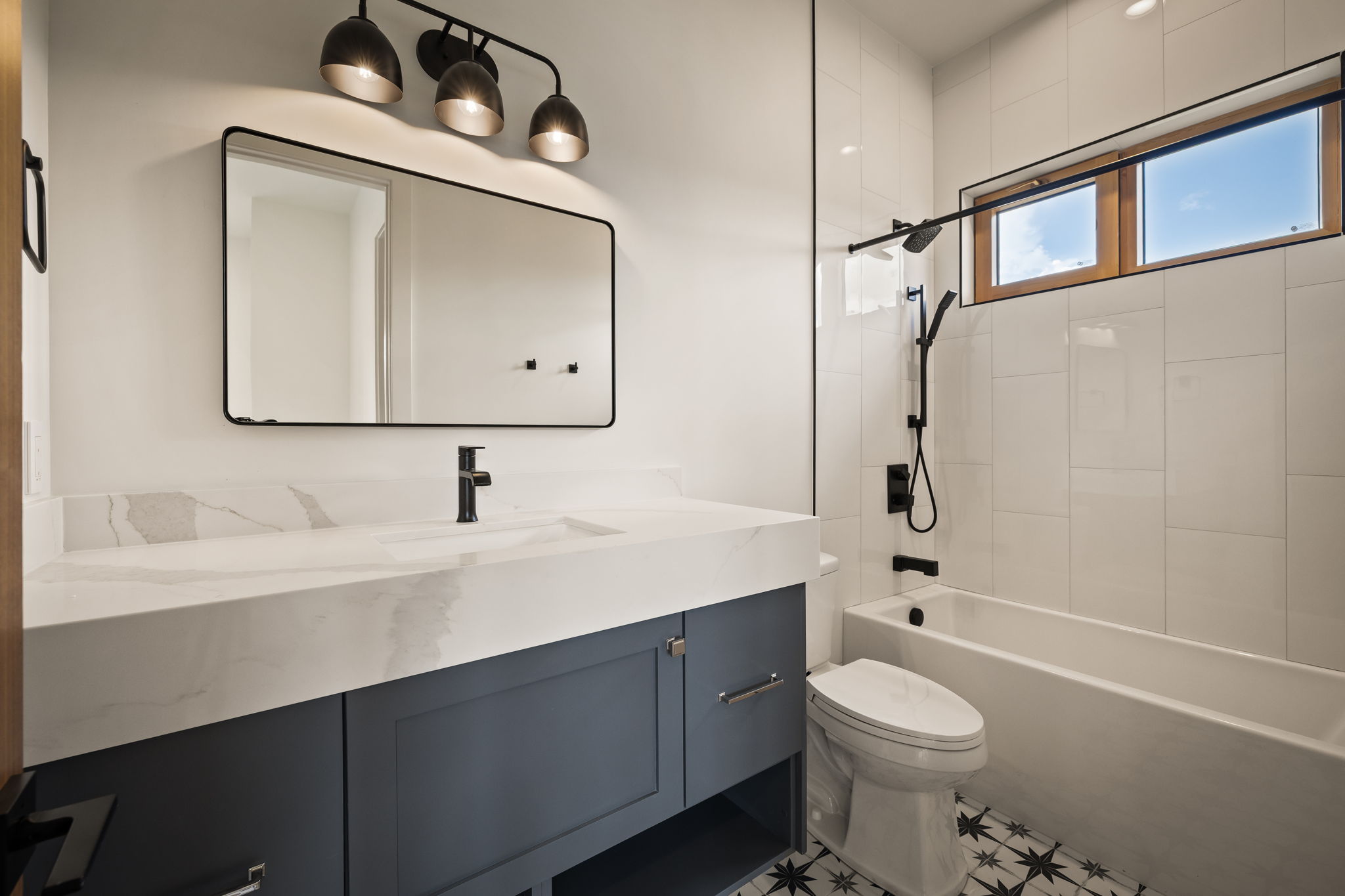 Modern bathroom featuring a dark blue vanity with a white solid-surface countertop and integrated sink