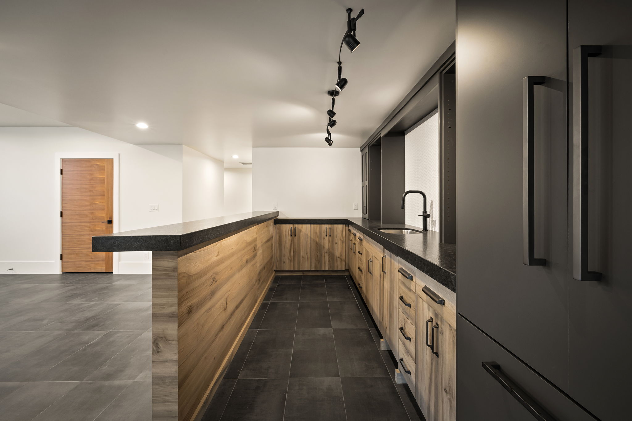 Kitchenette featuring wood-finish cabinetry, dark countertops, and a black faucet
