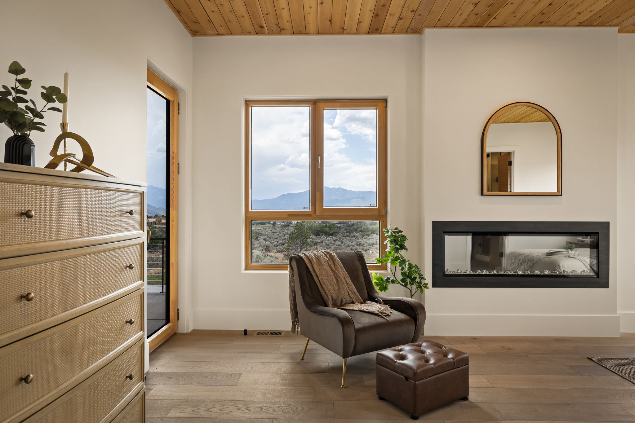 Integrated linear fireplace with a wood-finish mantel and a contemporary arched mirror