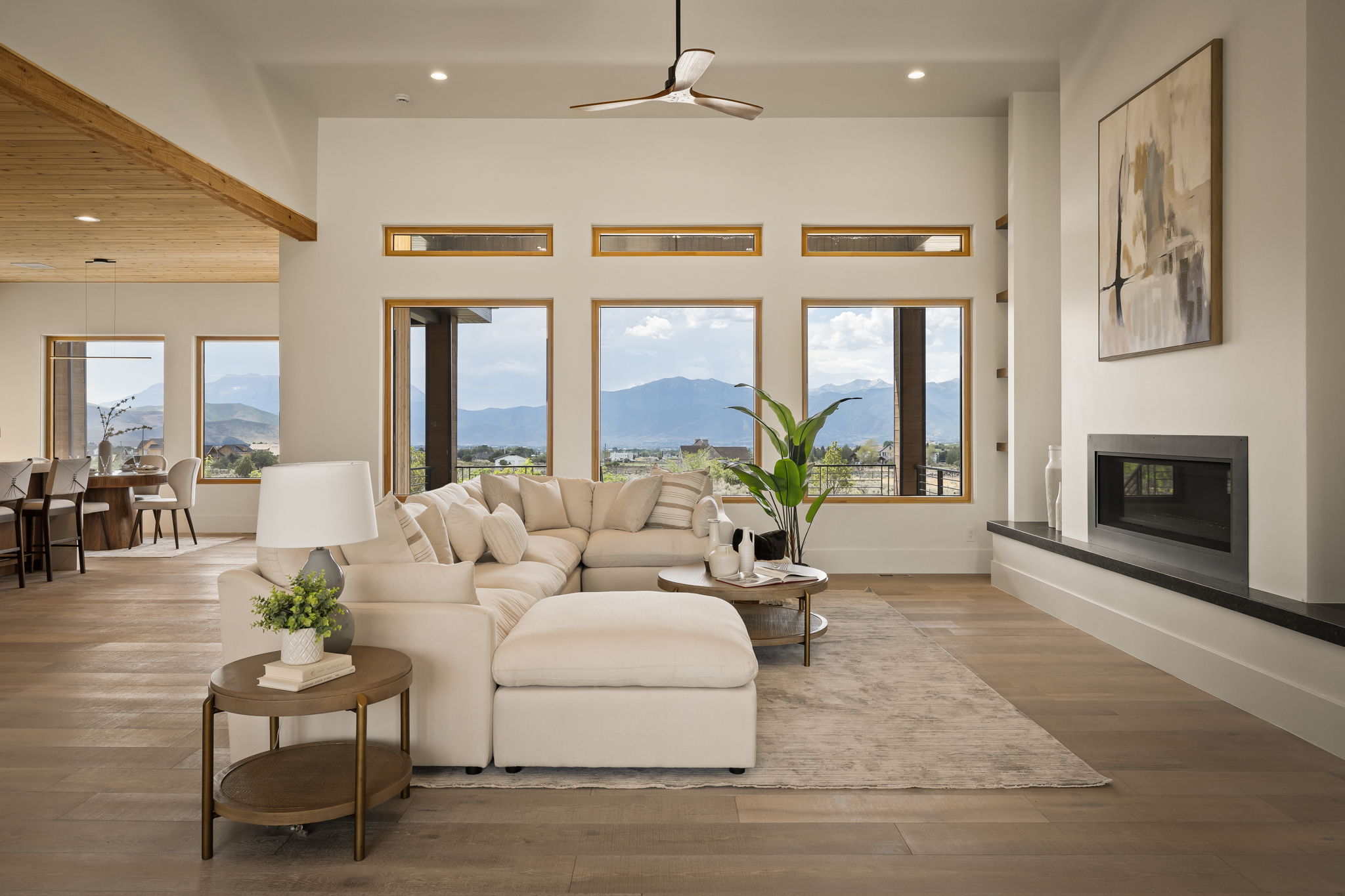 Spacious living area featuring high ceilings, wood-finish flooring, and a contemporary fireplace with a dark stone hearth