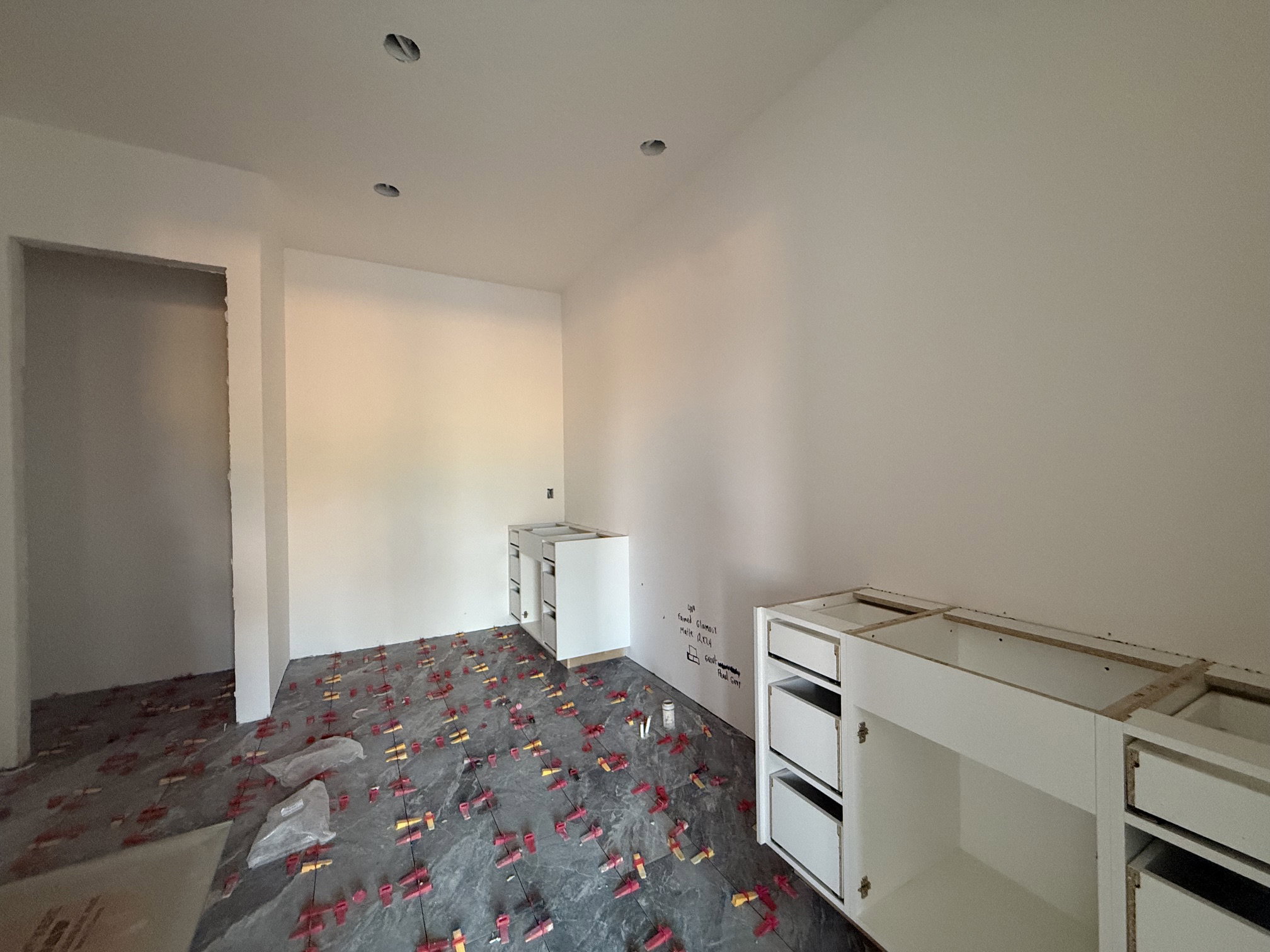 Unfinished room with recessed ceiling lighting, a door frame, and white base cabinetry