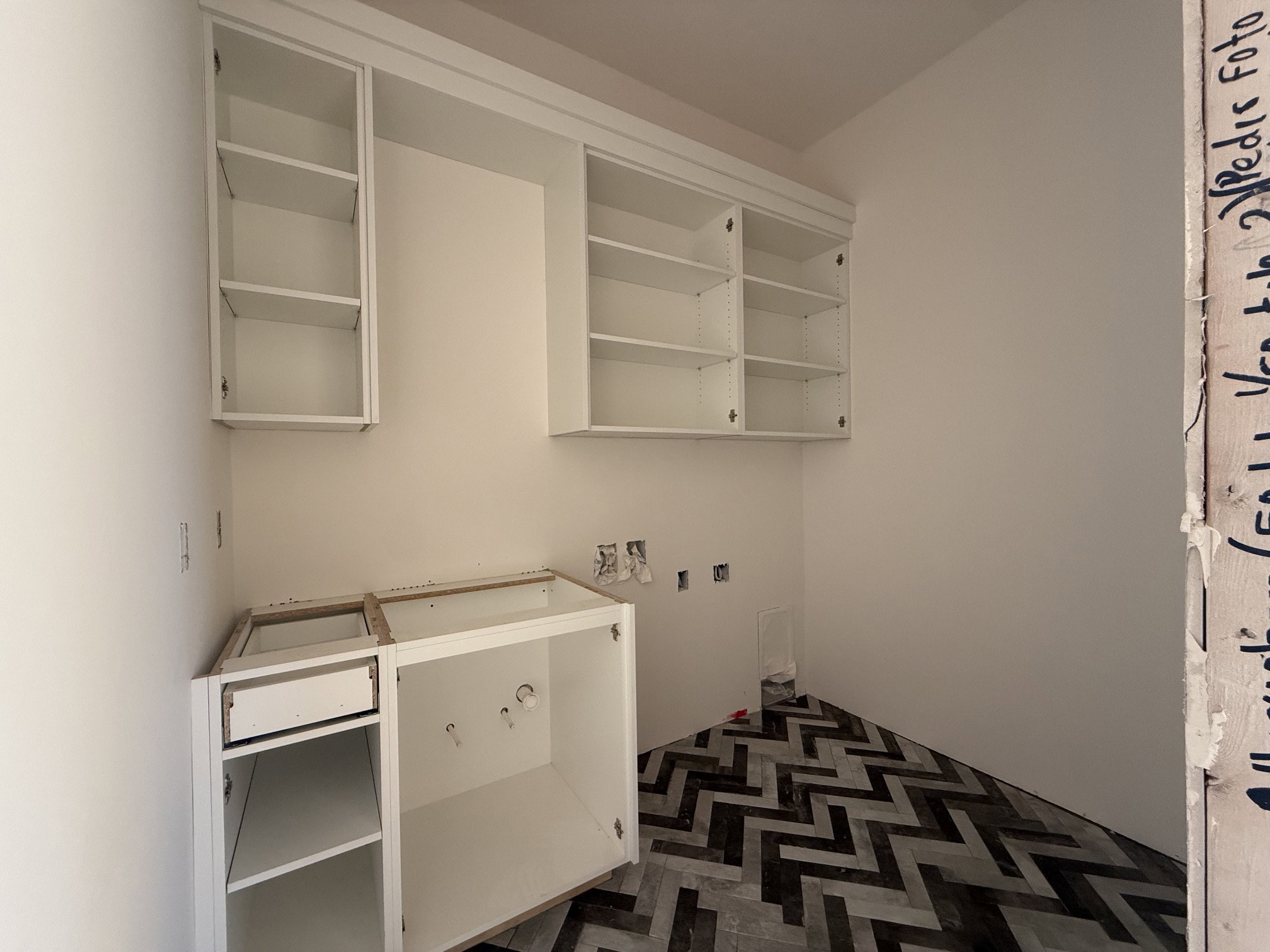Utility space featuring chevron-patterned flooring, white upper cabinetry, and white base cabinetry