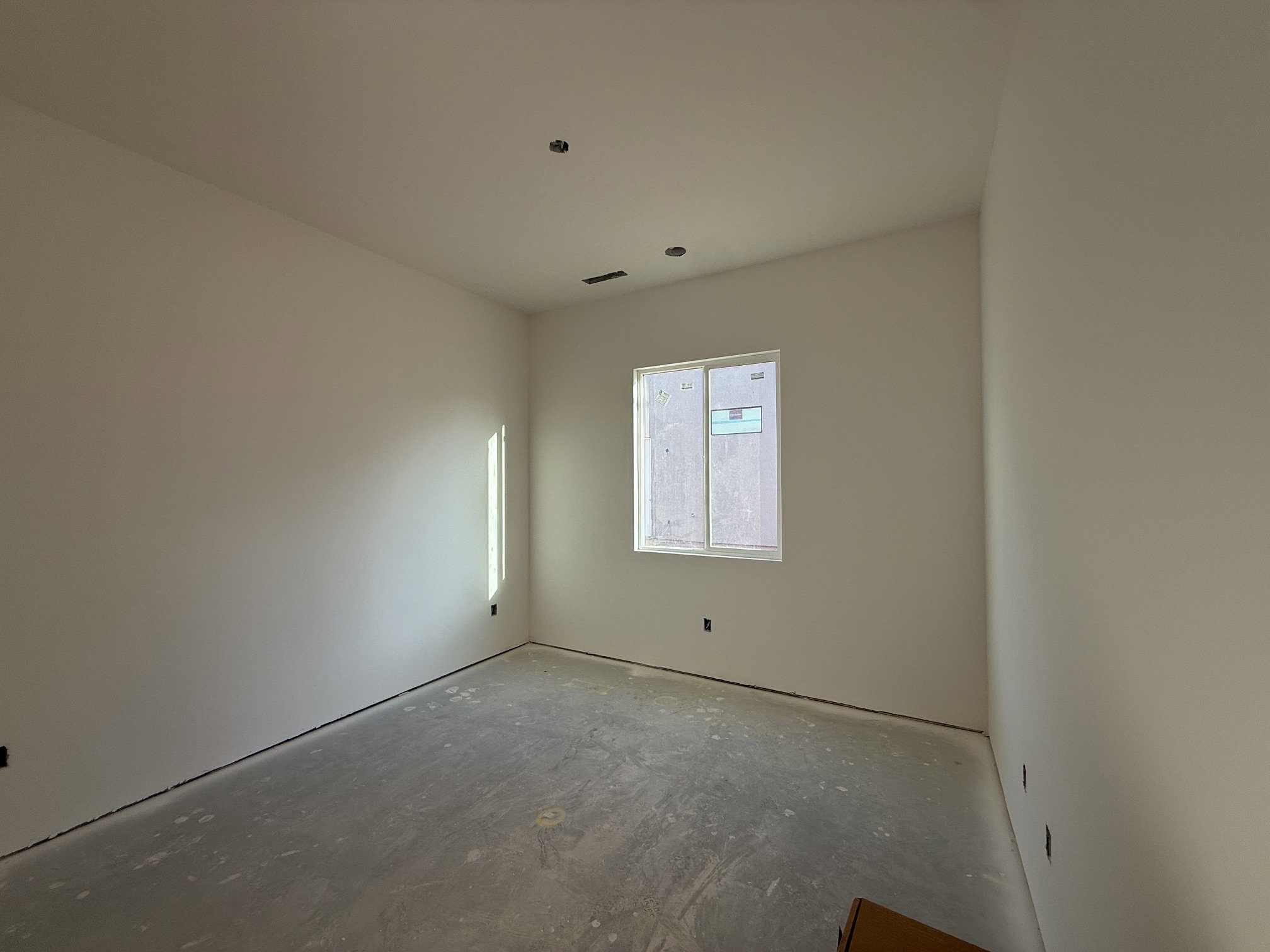 Interior room featuring a single window, white walls, and a concrete subfloor