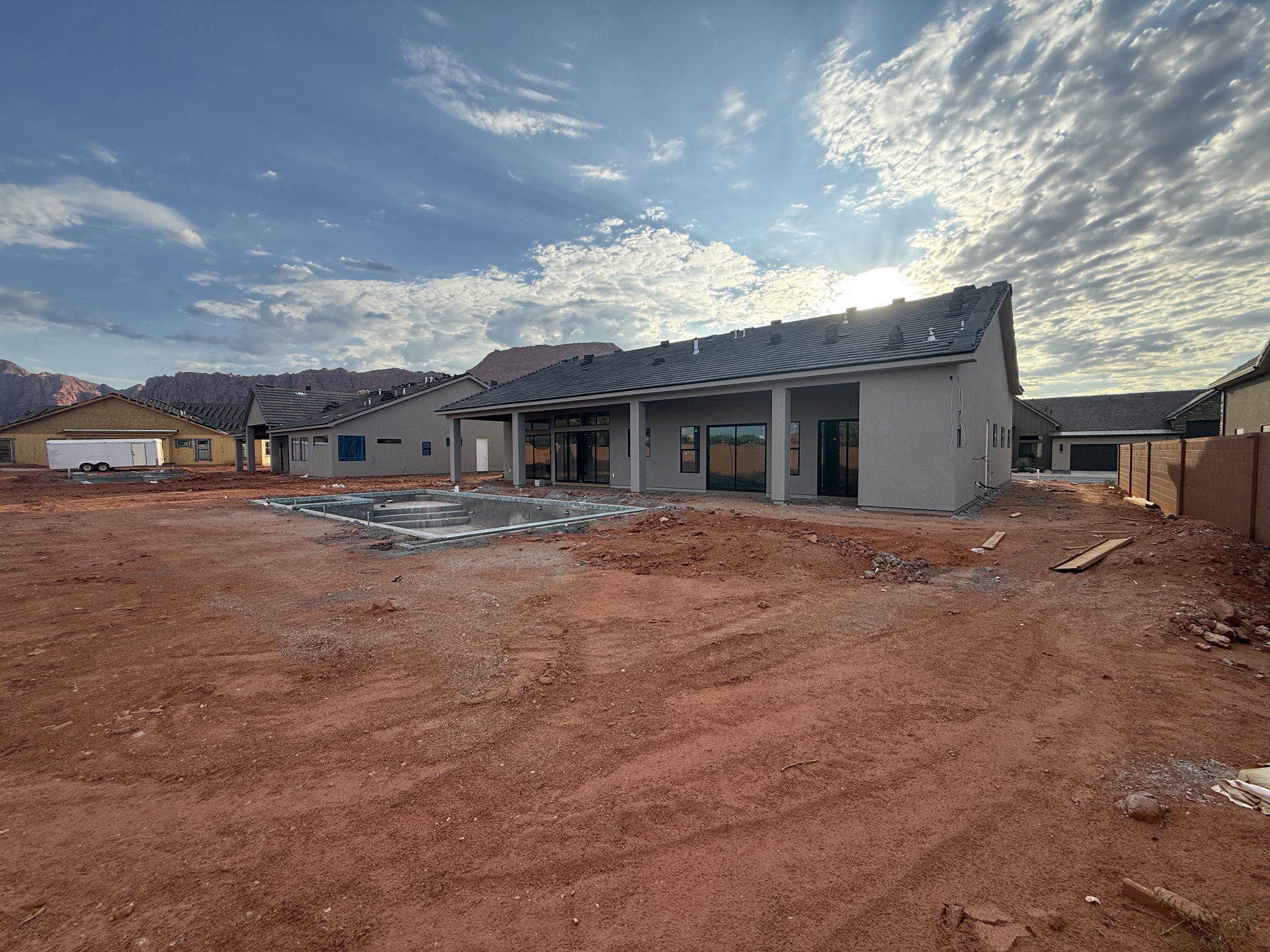 Newly constructed property featuring a gray stucco exterior and a partially completed in-ground pool