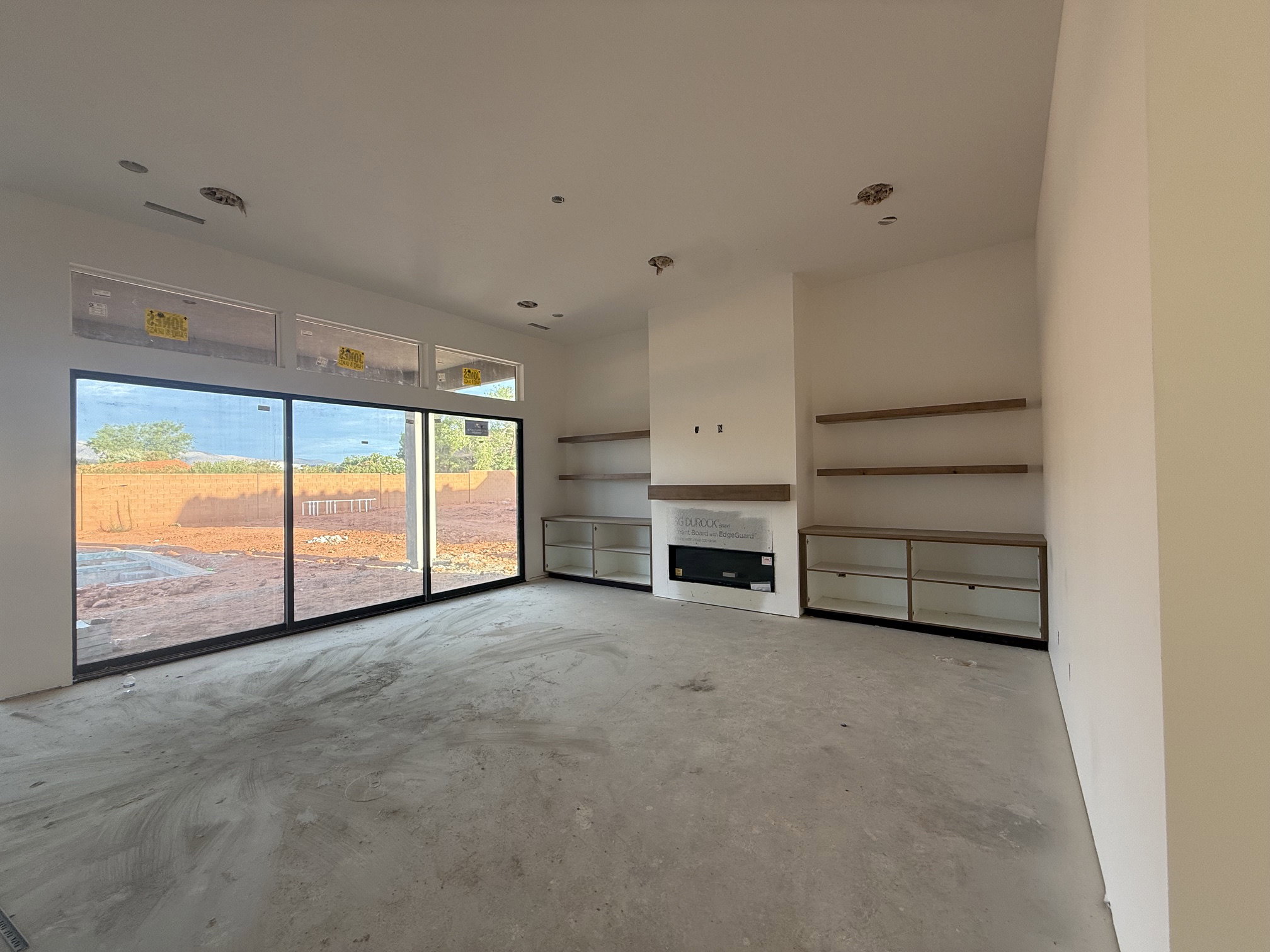 Spacious interior featuring a contemporary fireplace with wood mantel, built-in shelving, glass-front cabinetry, large sliding glass doors, and transom windows