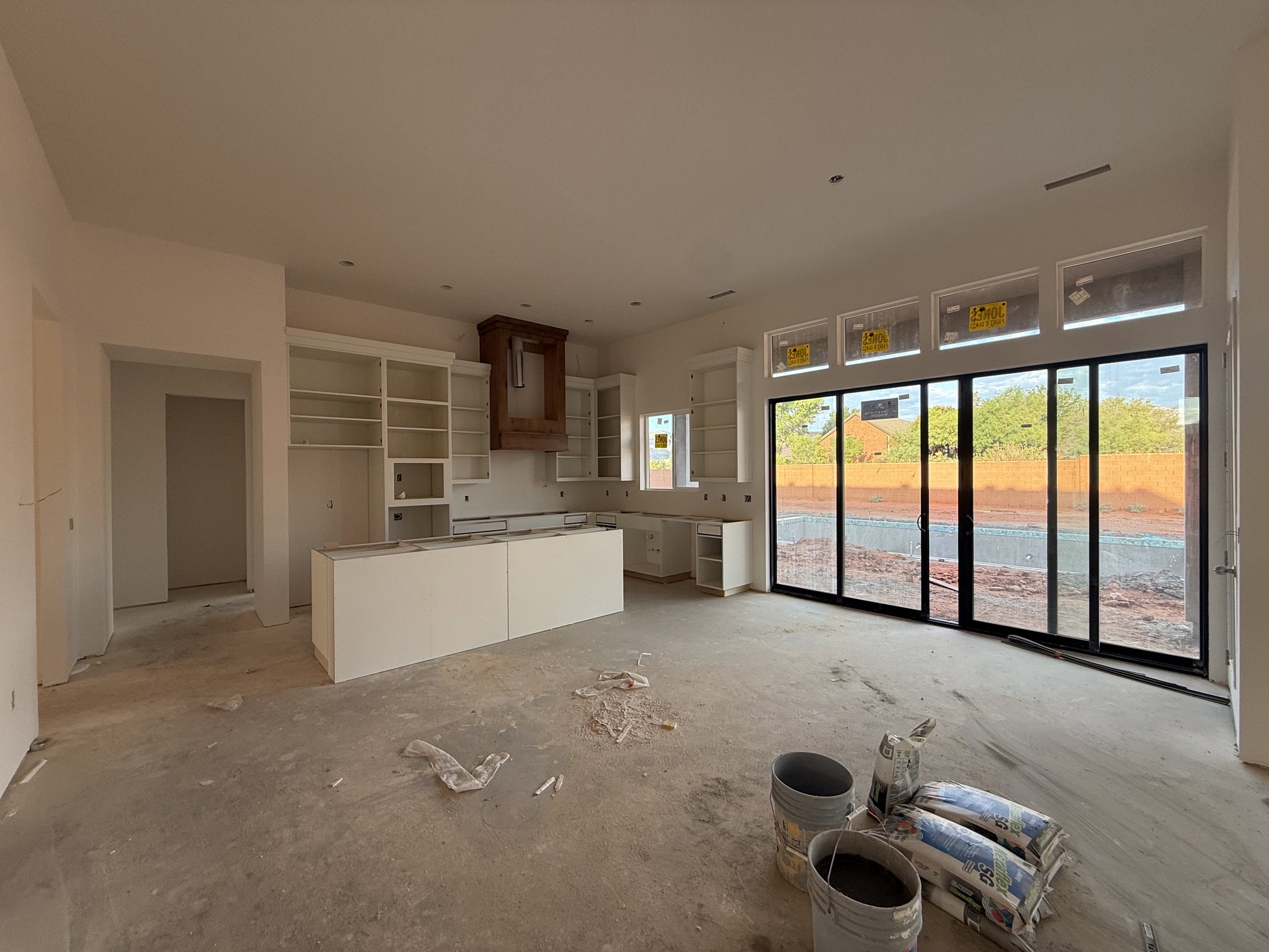 Spacious kitchen area featuring extensive white cabinetry, a large center island, a wood-finish range hood, and a wall of sliding glass doors