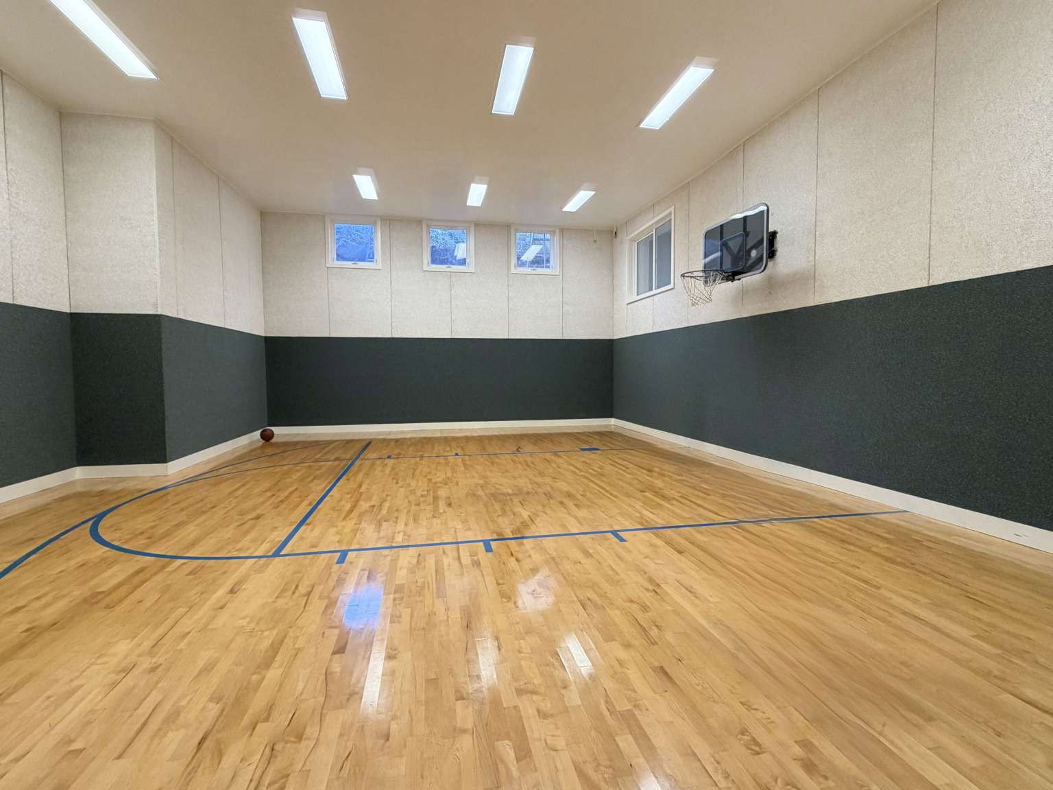 Indoor basketball court featuring hardwood flooring with blue game lines