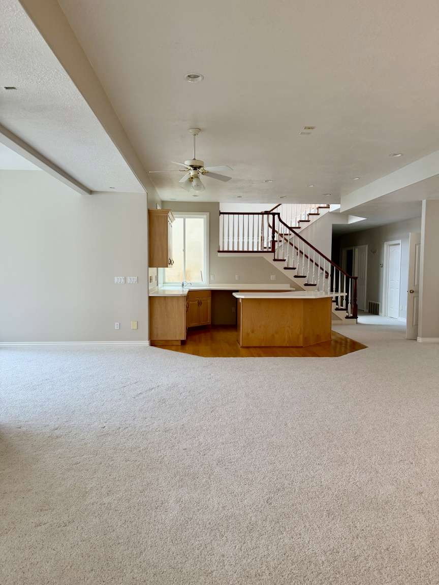 Open-concept living space featuring light-toned carpeting, recessed lighting, and a ceiling fan