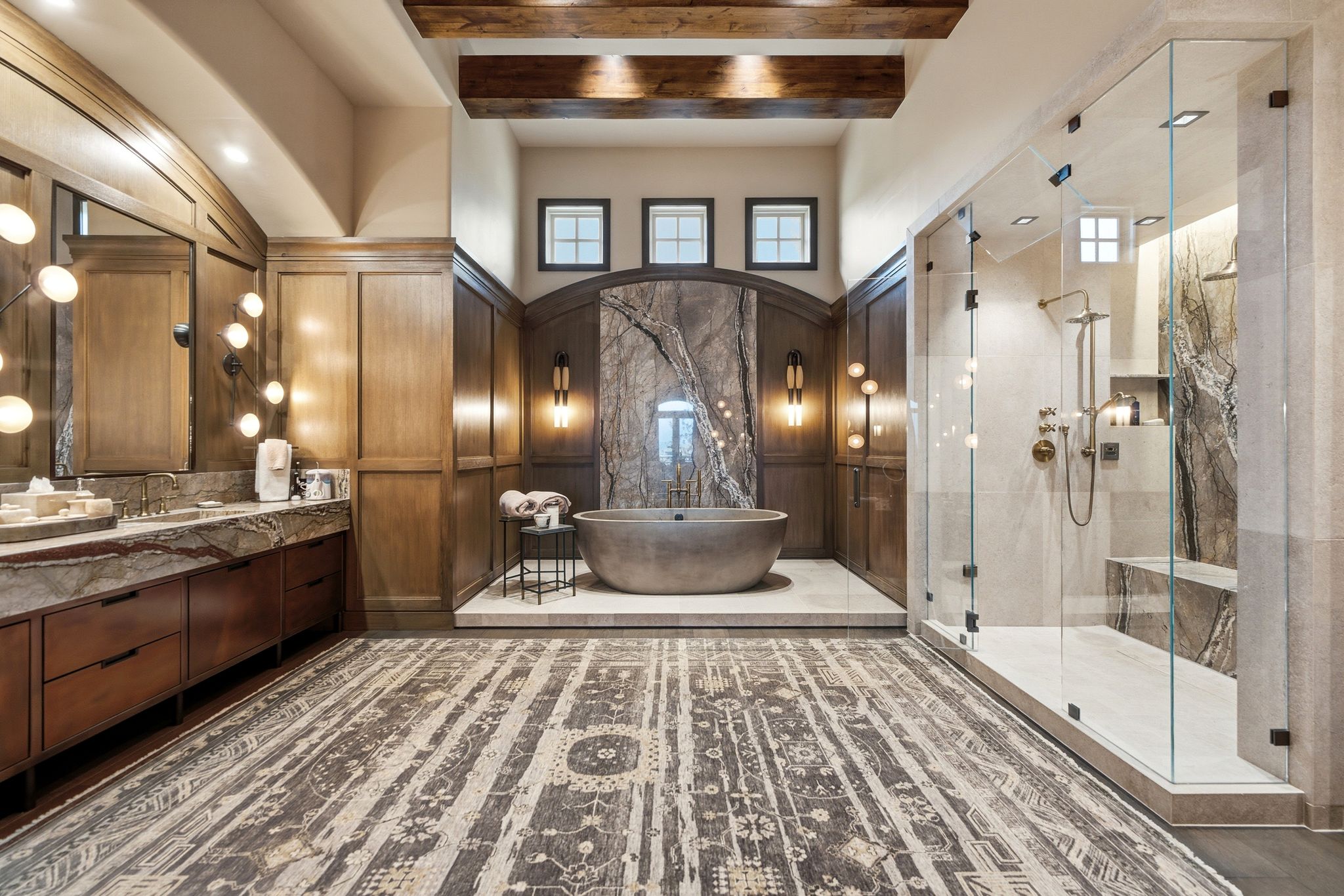 Freestanding soaking tub set against a dramatic stone accent wall