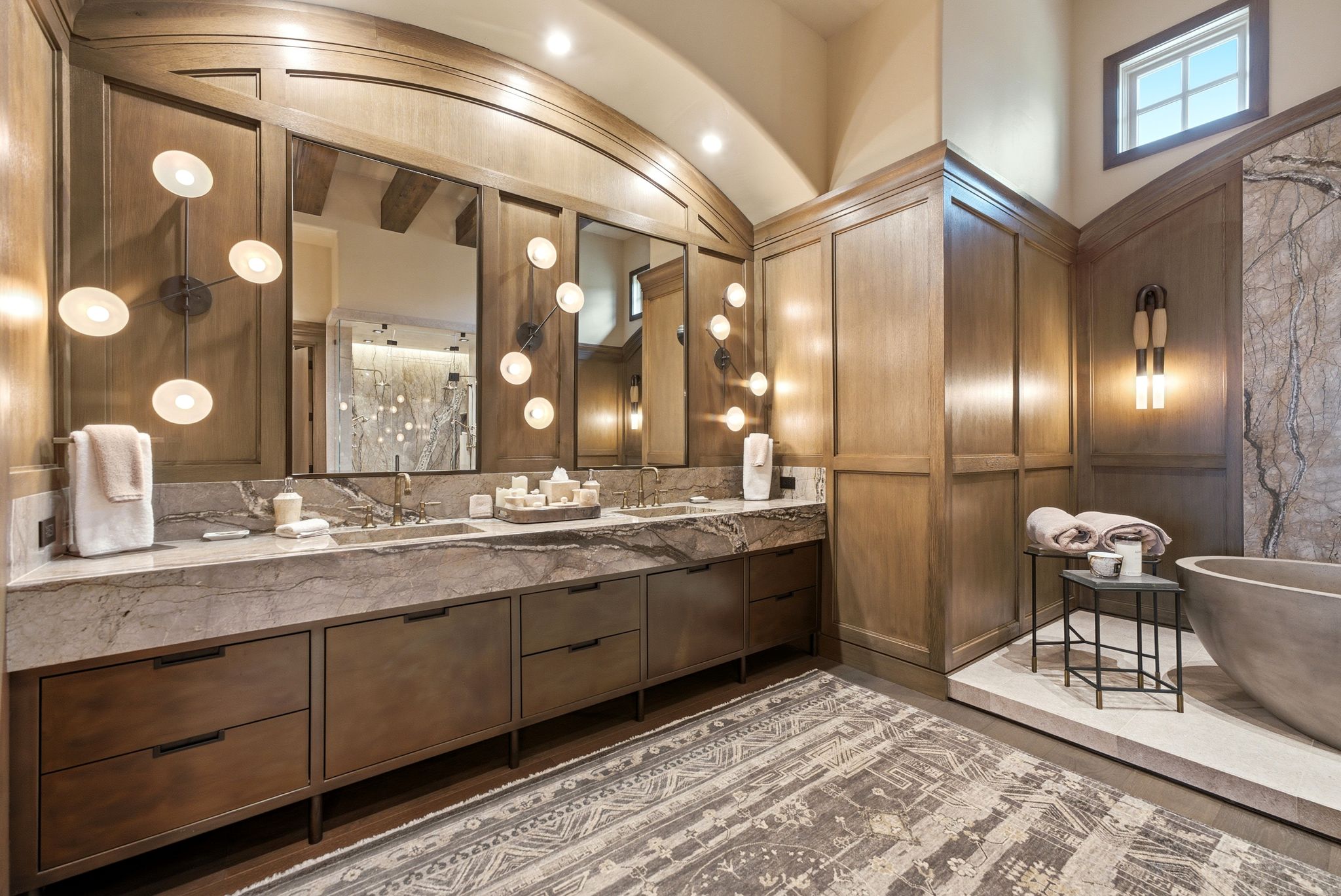 Dual vanity with stone countertop and undermount sinks, featuring a large mirror and contemporary wall sconces
