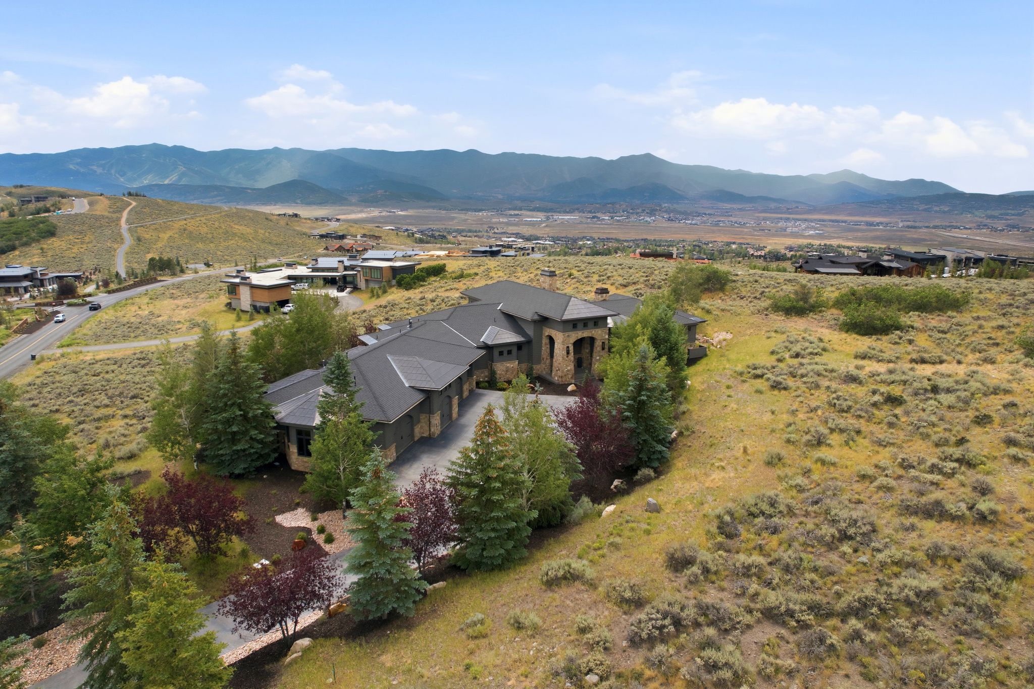 Expansive contemporary residence featuring a multi-car garage, stone and stucco exterior, and a dark shingle roof