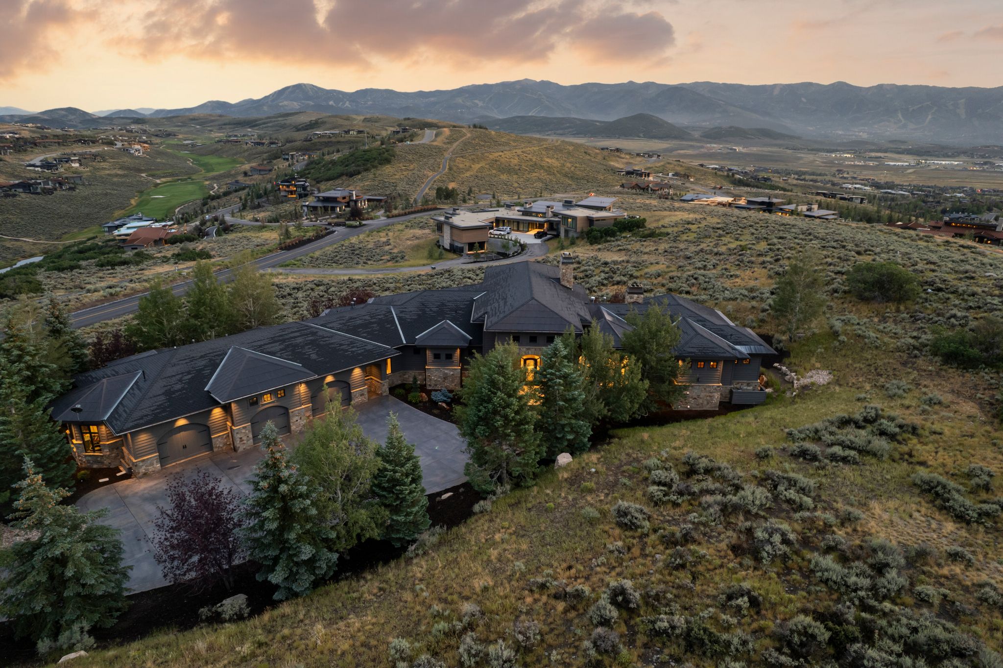 Expansive property featuring a stone and siding exterior, multiple gabled roofs, and a multi-car garage with arched doors