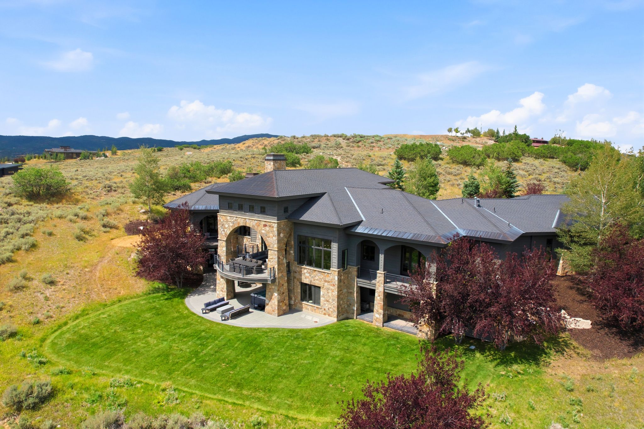 Stone and stucco exterior with multiple balconies and a lower-level patio