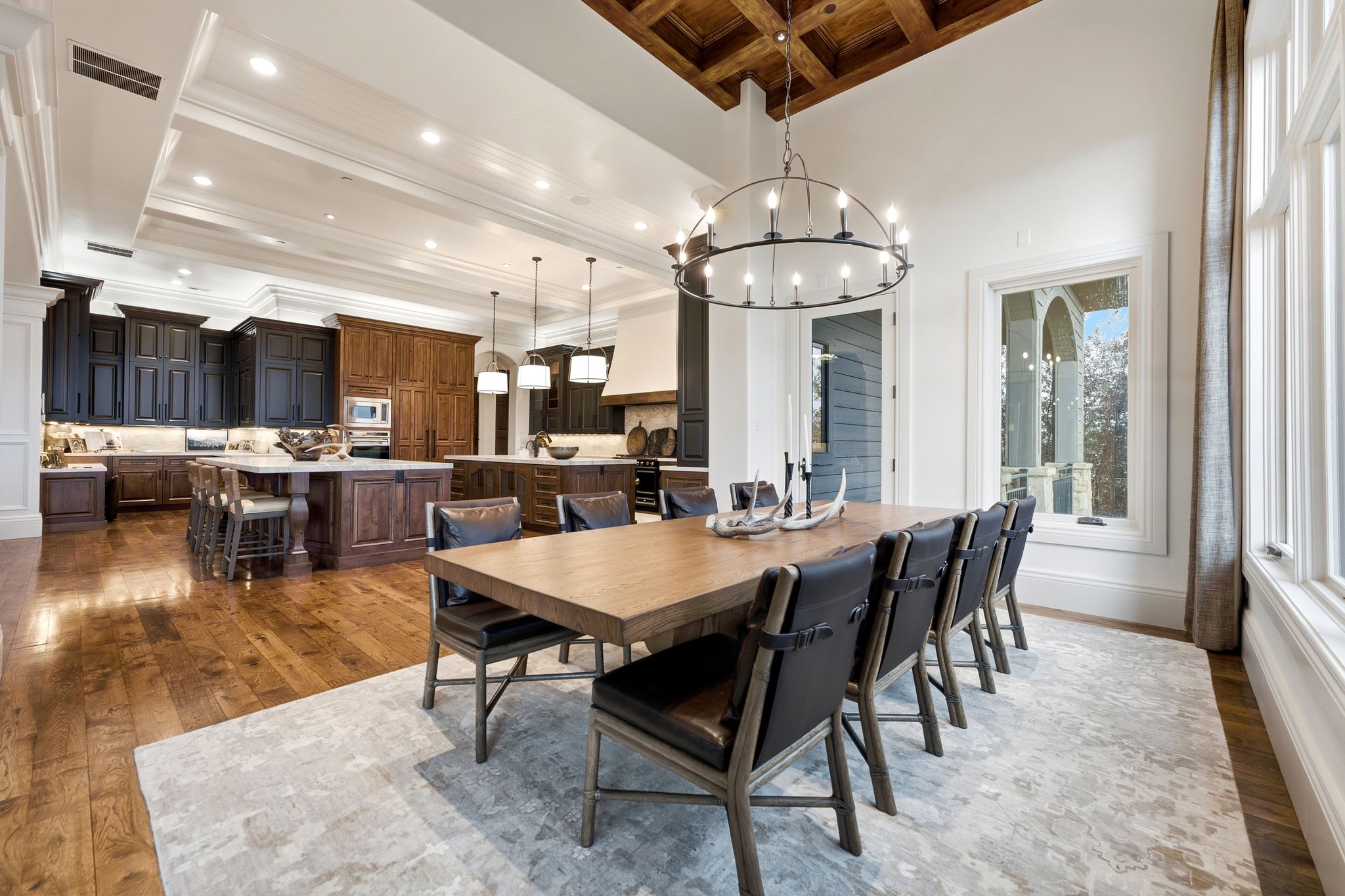 Spacious dining area with coffered wood ceiling, large picture windows, and an open concept layout to the kitchen