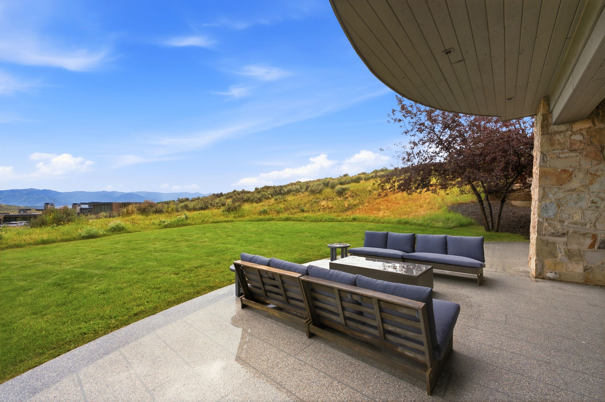 Expansive outdoor patio featuring stone-clad columns and a curved overhead structure