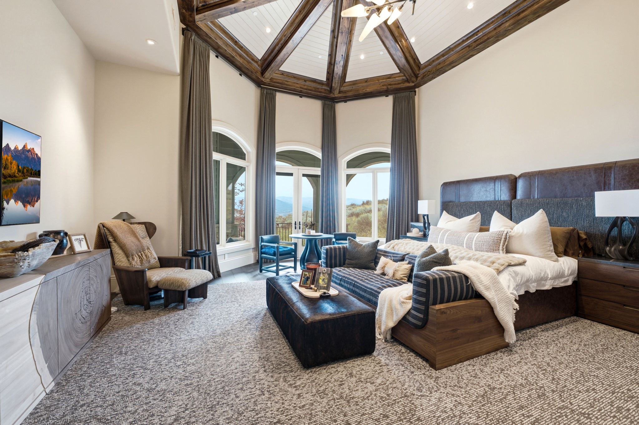 Spacious room featuring a vaulted ceiling with exposed wood beams and white paneling