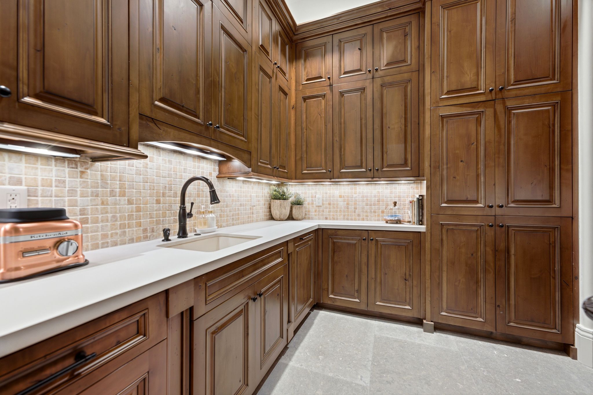 Extensive dark wood cabinetry, white countertops, and a mosaic tile backsplash