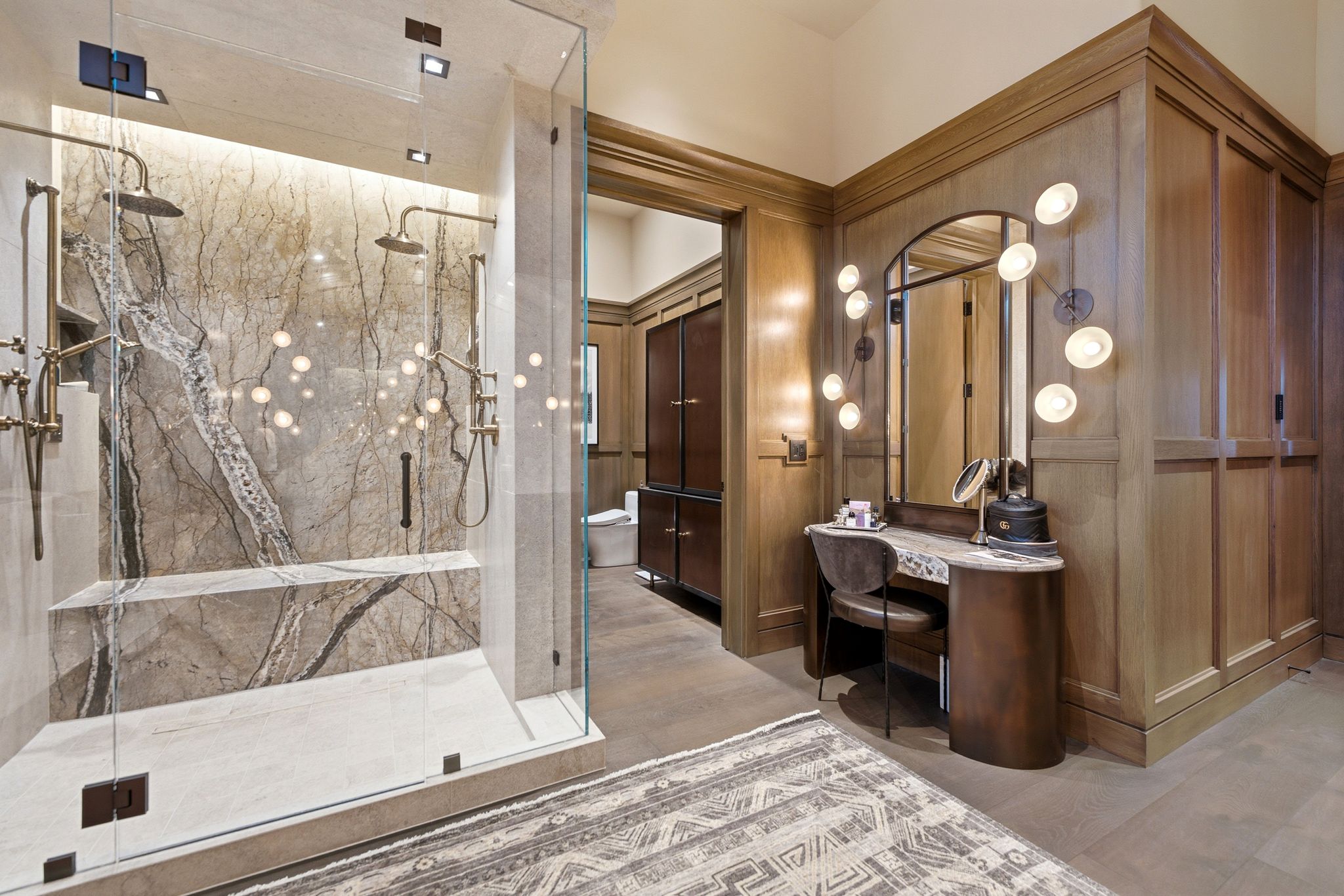 Spa-inspired shower with glass enclosure, dual showerheads, integrated seating, and large-format veined wall tile