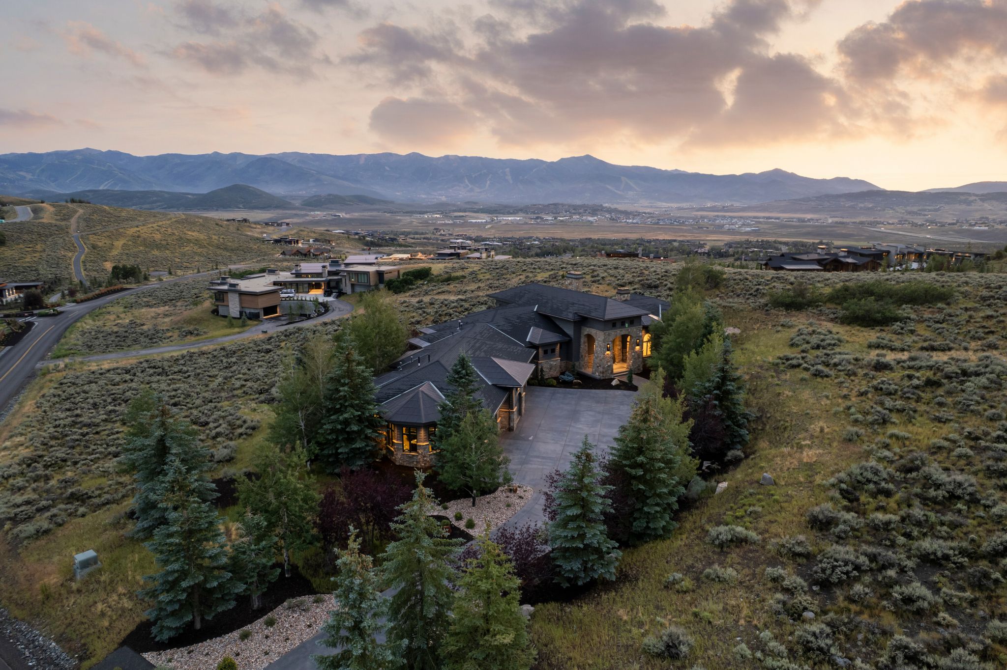 Expansive property featuring a stone and stucco exterior, dark shingle roofing, and a paved driveway