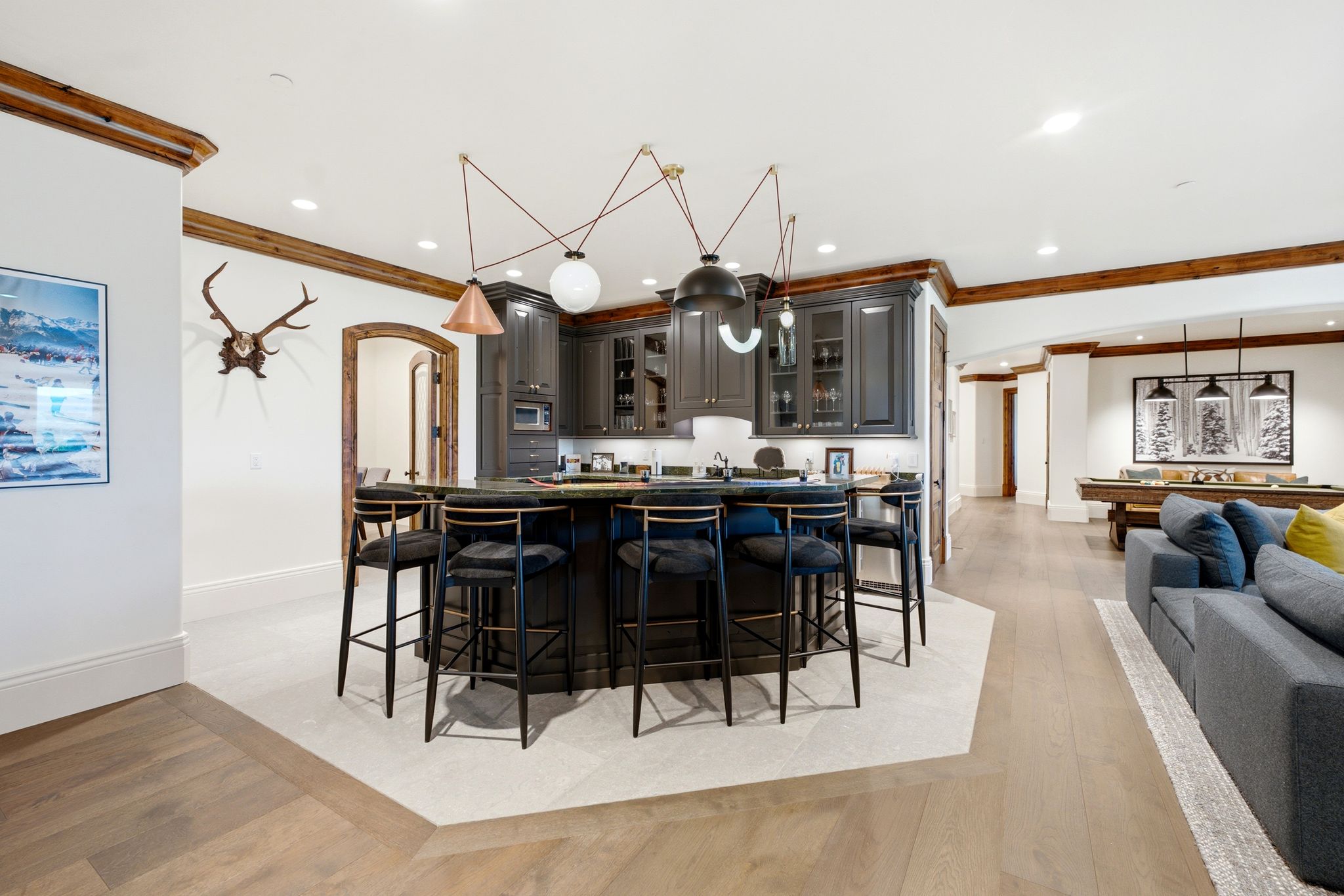 Central wet bar featuring dark cabinetry, dark countertop, and integrated sink