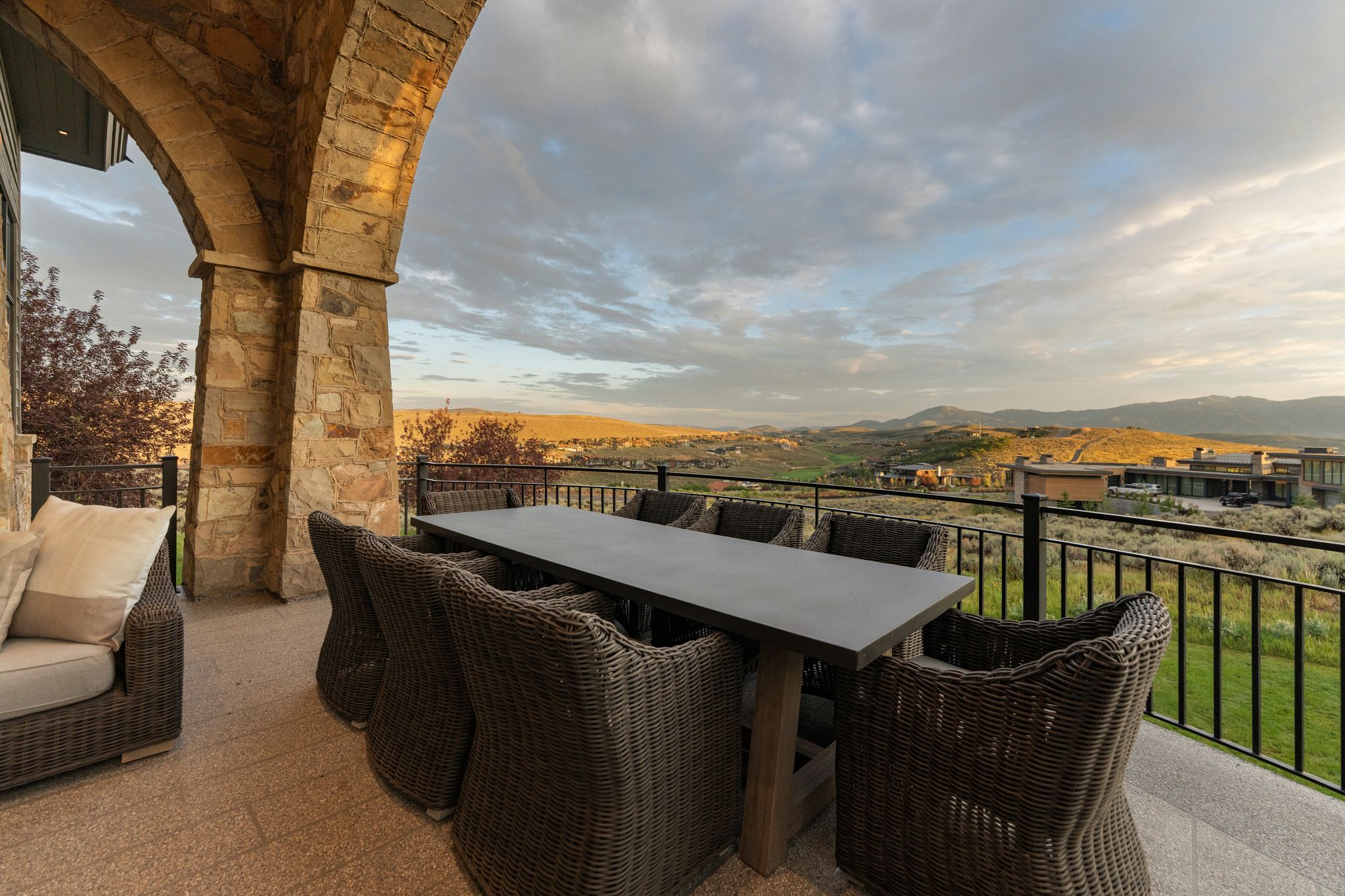 Expansive covered patio featuring stone archways, a textured tile floor, and a black metal railing