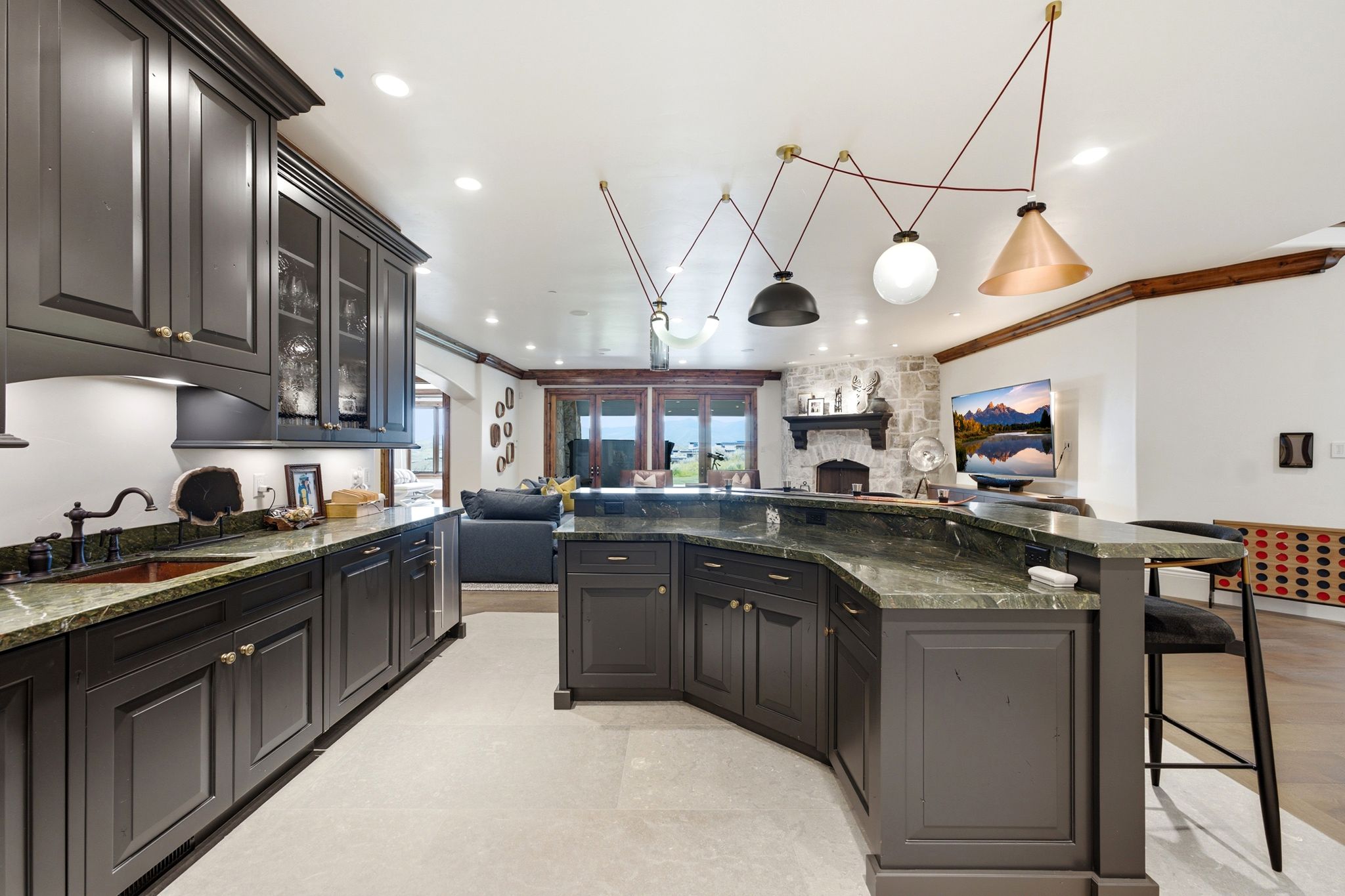 Kitchen featuring dark cabinetry, green stone countertops, a bronze basin sink, and under-cabinet lighting