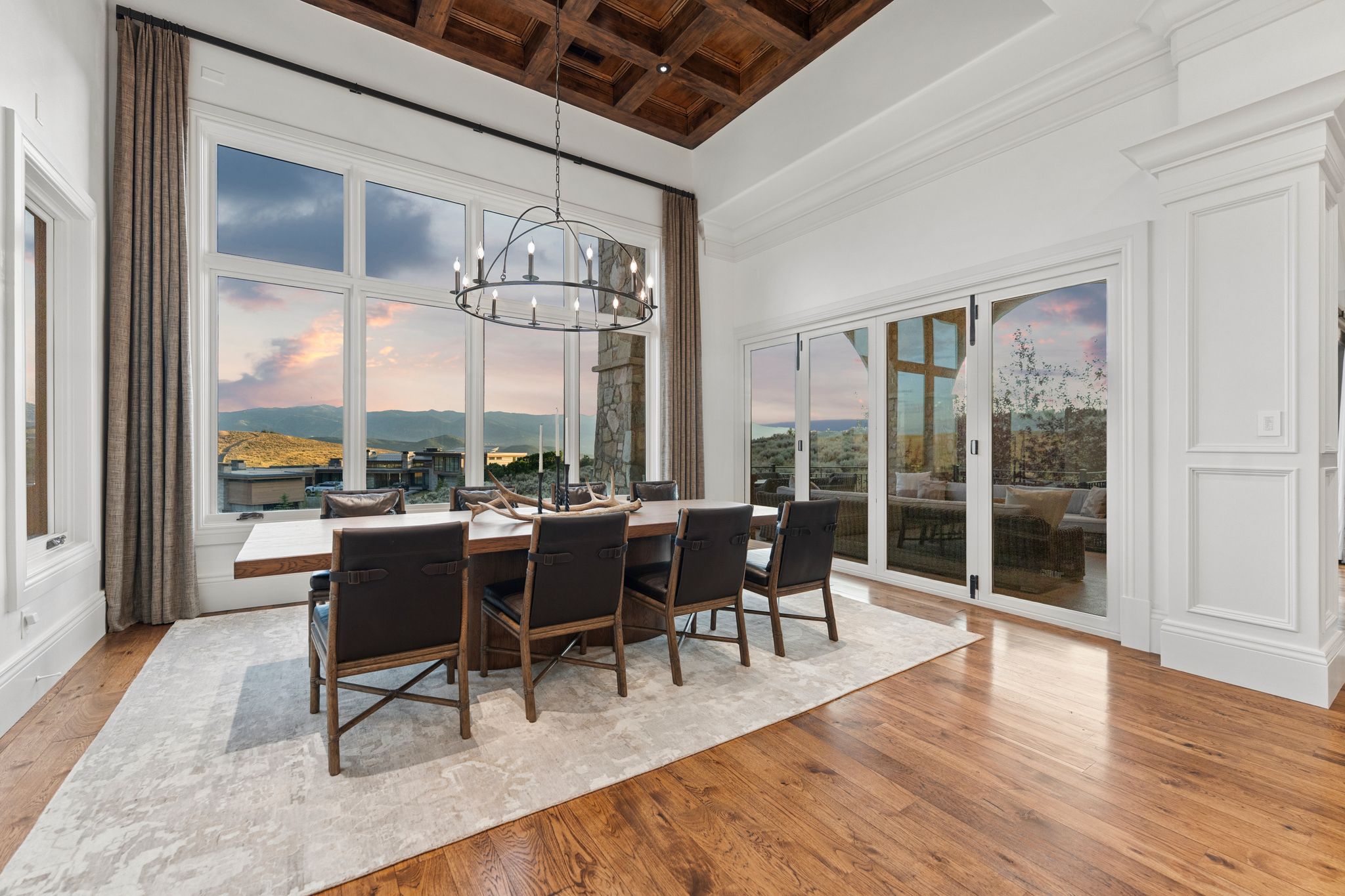 Great room featuring a coffered wood ceiling, expansive window wall, rich wood-finish flooring, and white trim work