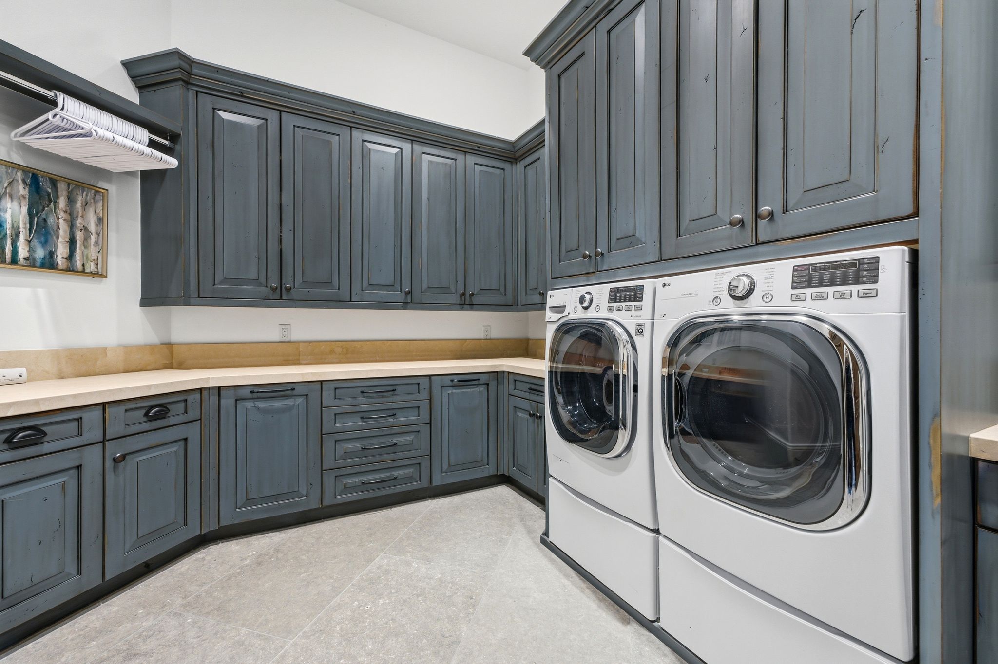 Dedicated laundry area featuring abundant distressed blue cabinetry with dark hardware