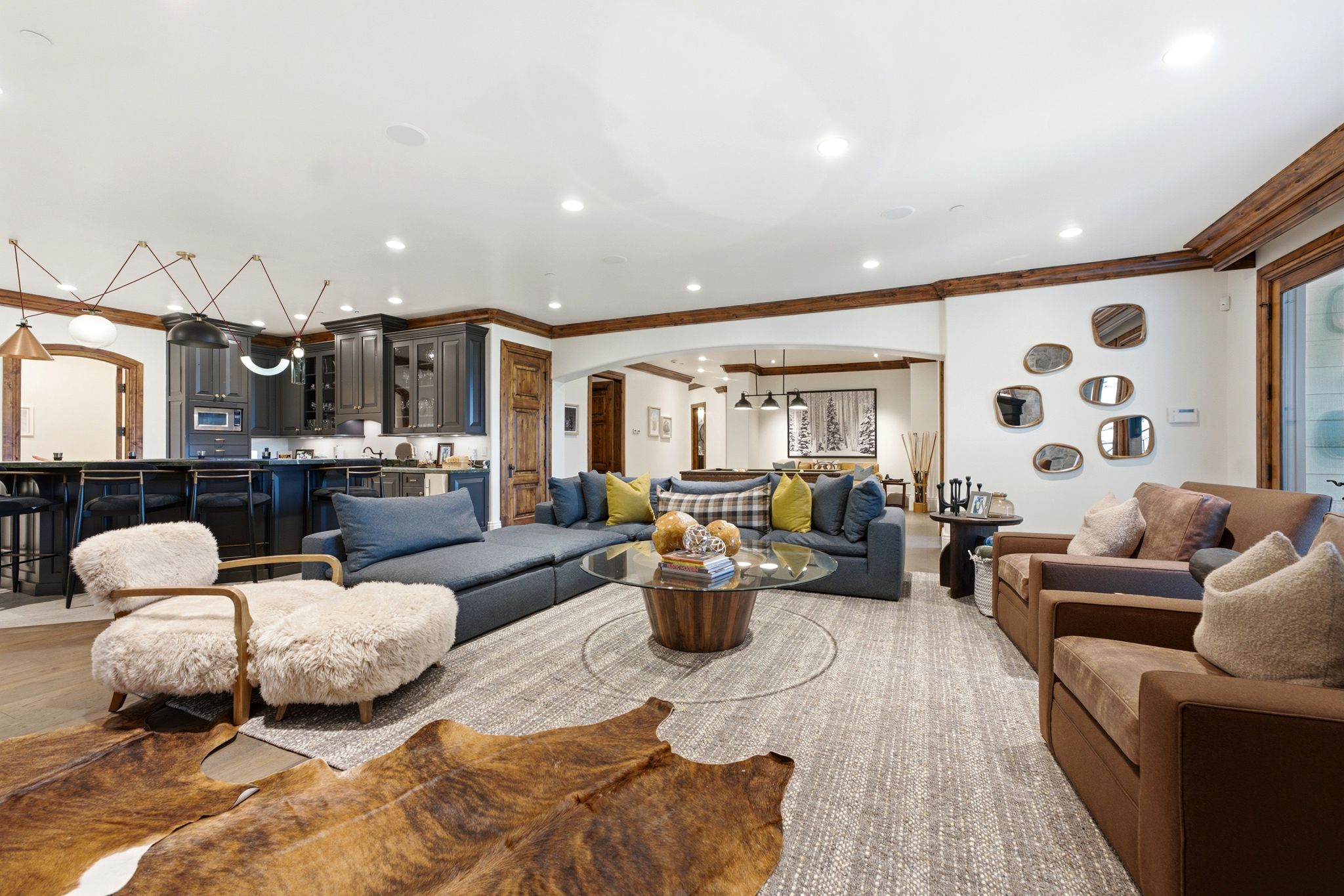 Open-concept living area featuring wood-finish flooring, a contemporary ceiling light fixture, wood beam accents, and recessed lighting