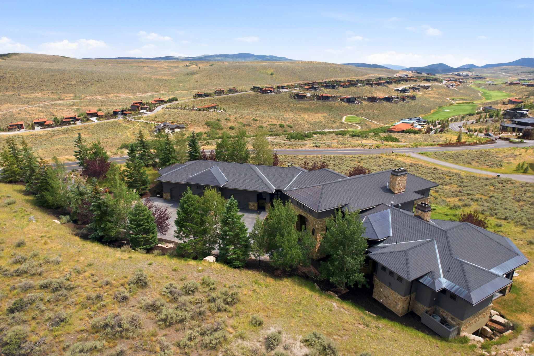 Expansive property featuring a multi-level residence with dark roofing and stone accents