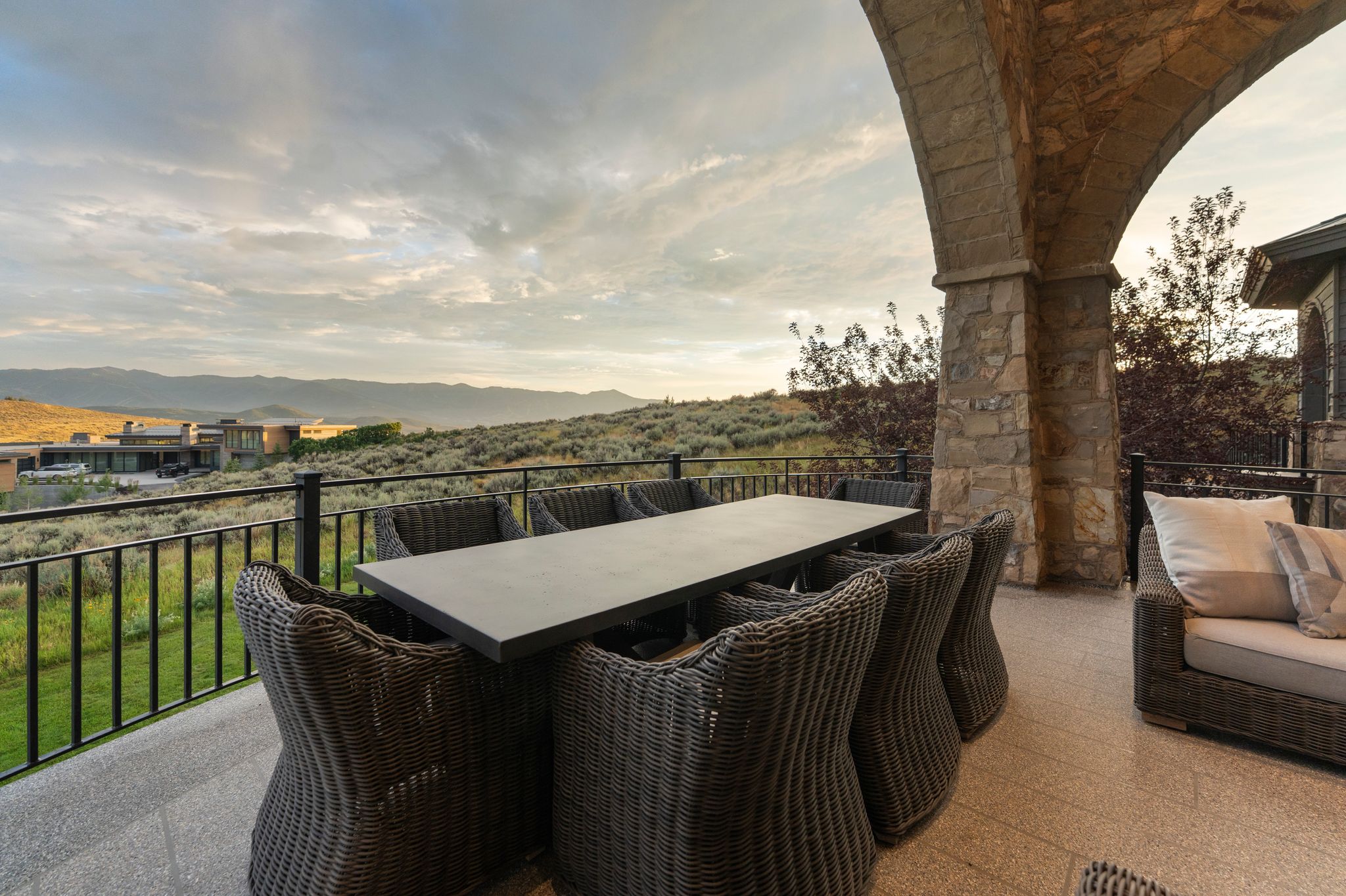 Expansive outdoor patio featuring a stone archway, tile flooring, and a black metal railing