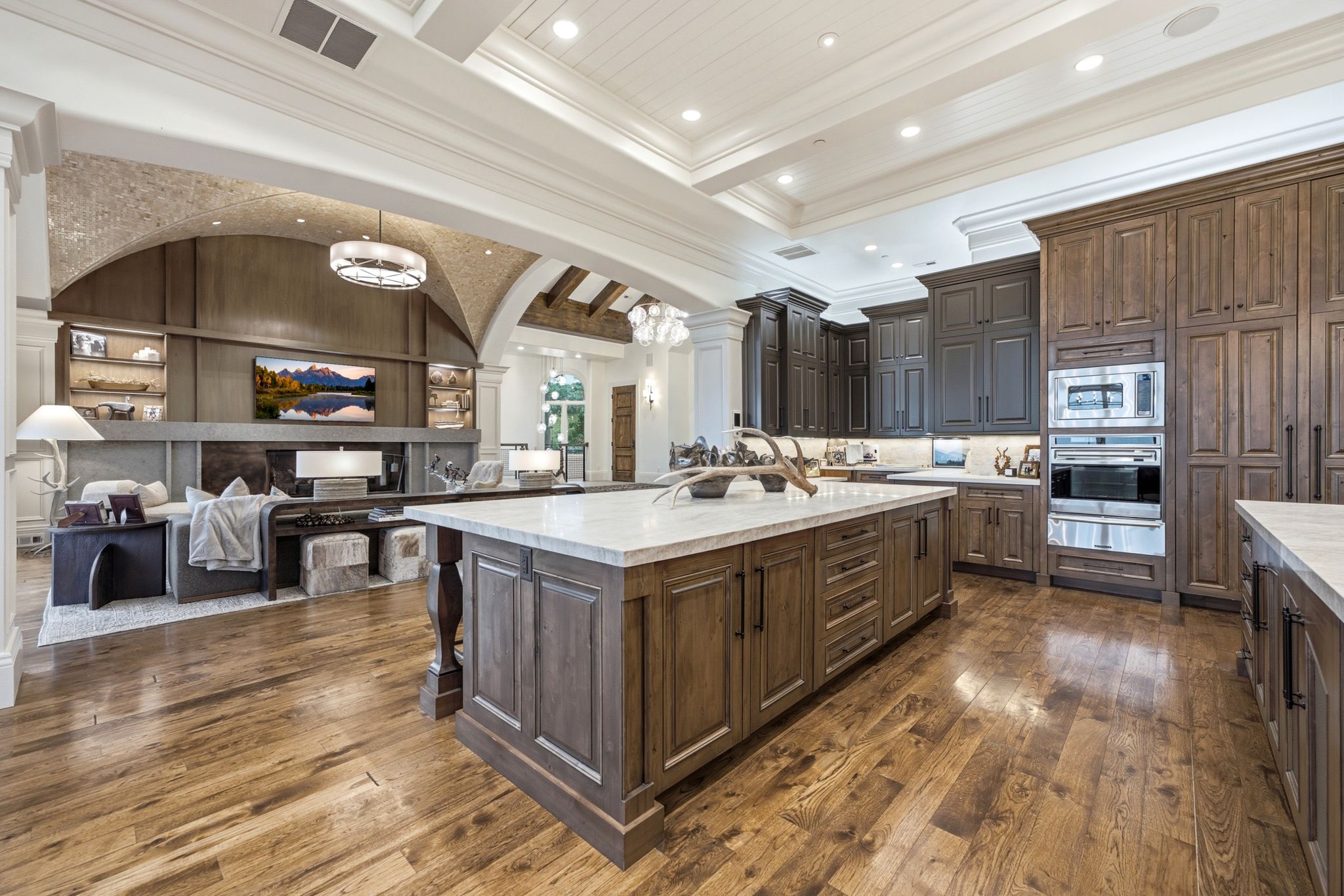 Expansive gourmet kitchen featuring wood-finish cabinetry, integrated stainless steel appliances, and a large central island with a light-toned countertop