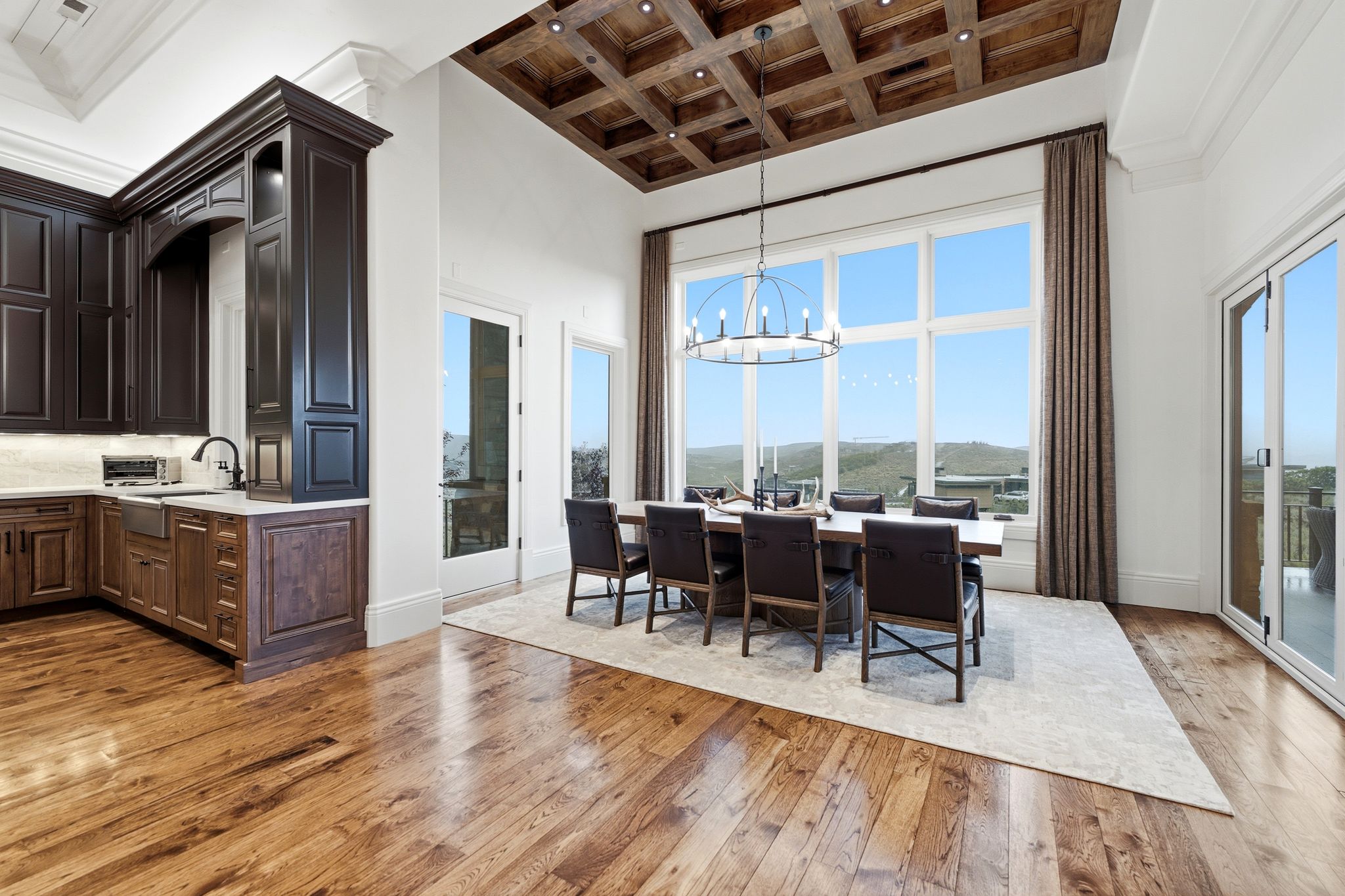 Grand dining area featuring a coffered wood-finish ceiling, expansive windows, a large chandelier, and wood-finish flooring