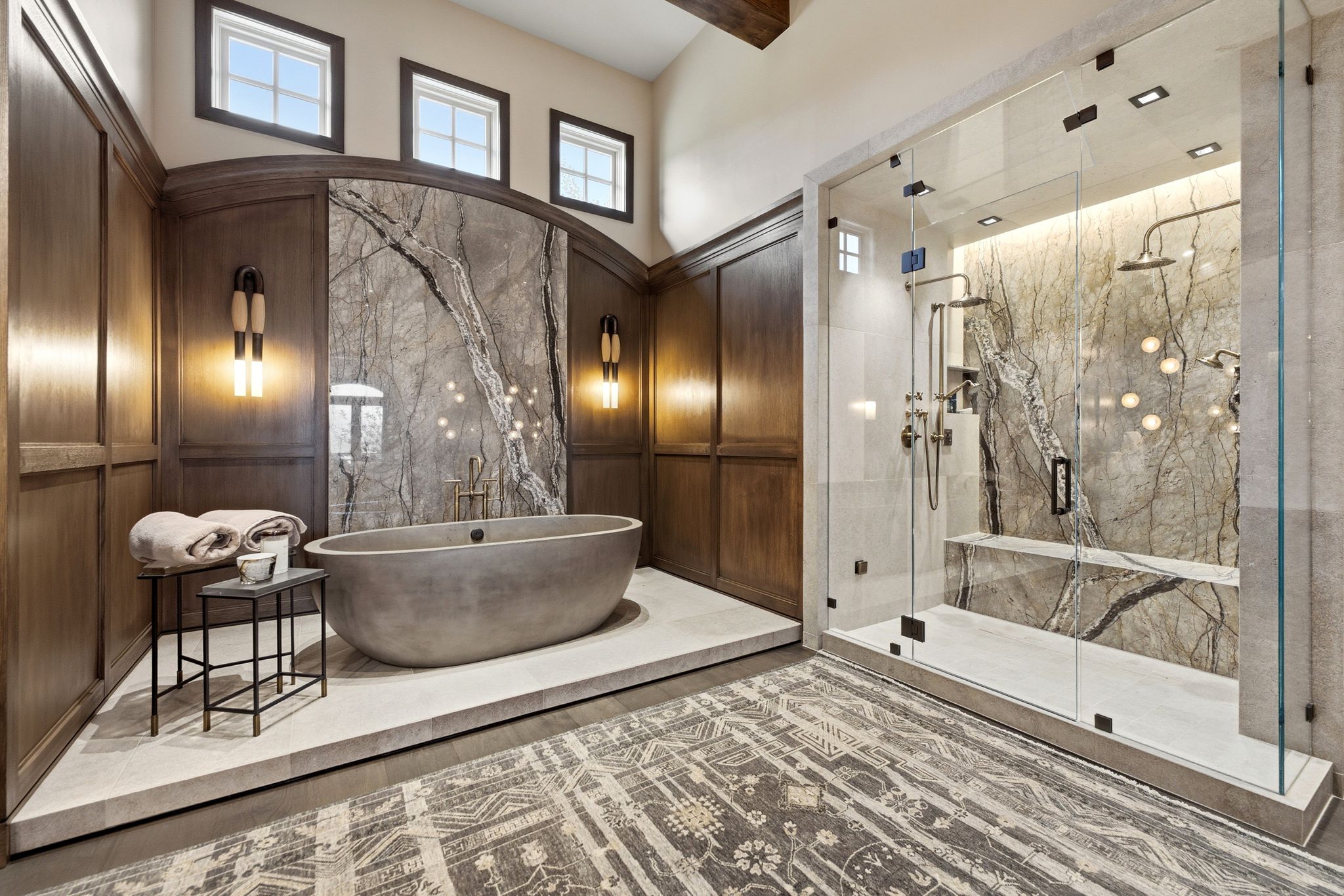 Luxurious bathroom featuring a freestanding soaking tub, a spacious glass-enclosed shower with a built-in bench, and striking natural stone accent walls