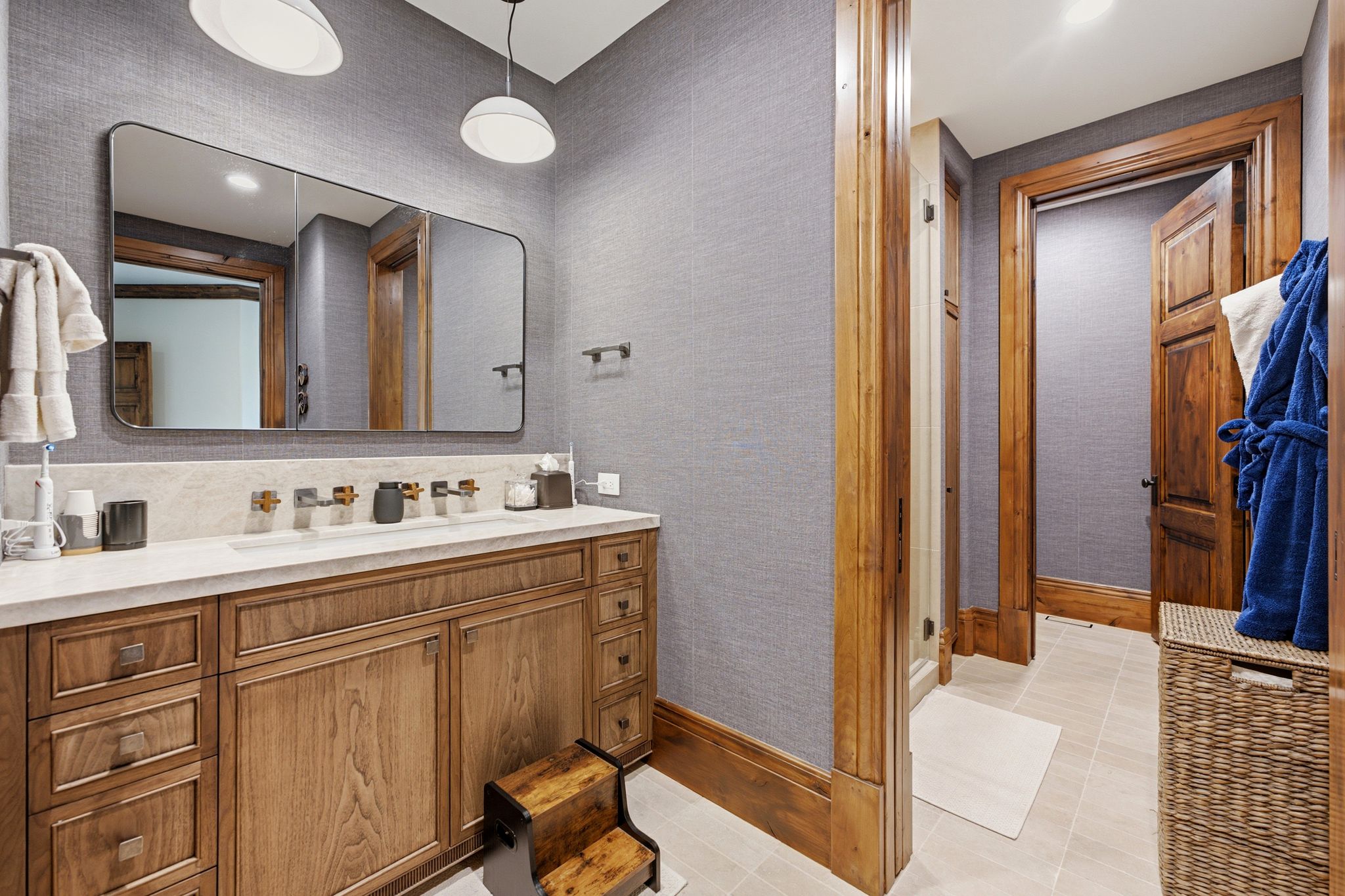 Bathroom featuring a double vanity with stone countertop, wood-finish cabinetry, and wall-mounted faucets