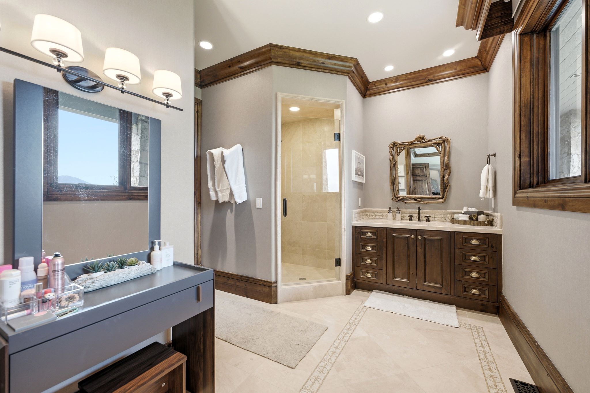 Bathroom featuring a dark wood vanity with a light-toned countertop, a glass-enclosed shower, and tile flooring with decorative inlay