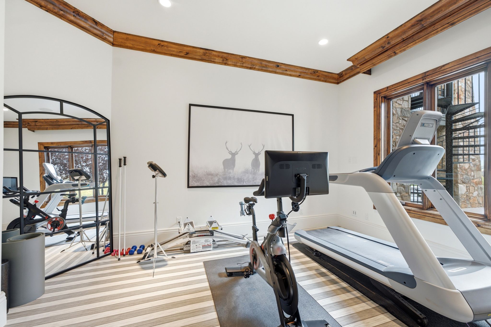 Dedicated exercise space featuring a large window with natural wood trim, recessed lighting, and decorative wood ceiling beams