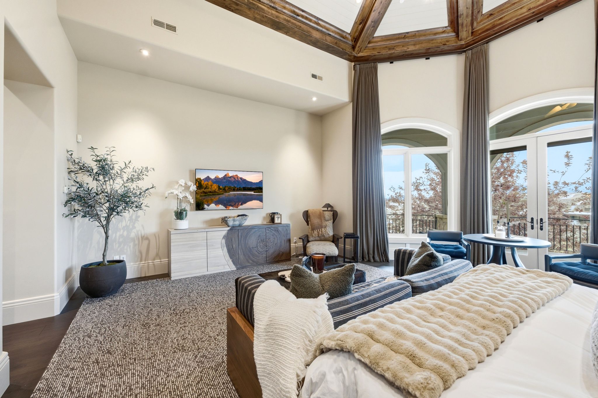 Vaulted wood-beamed ceiling with arched windows and French doors