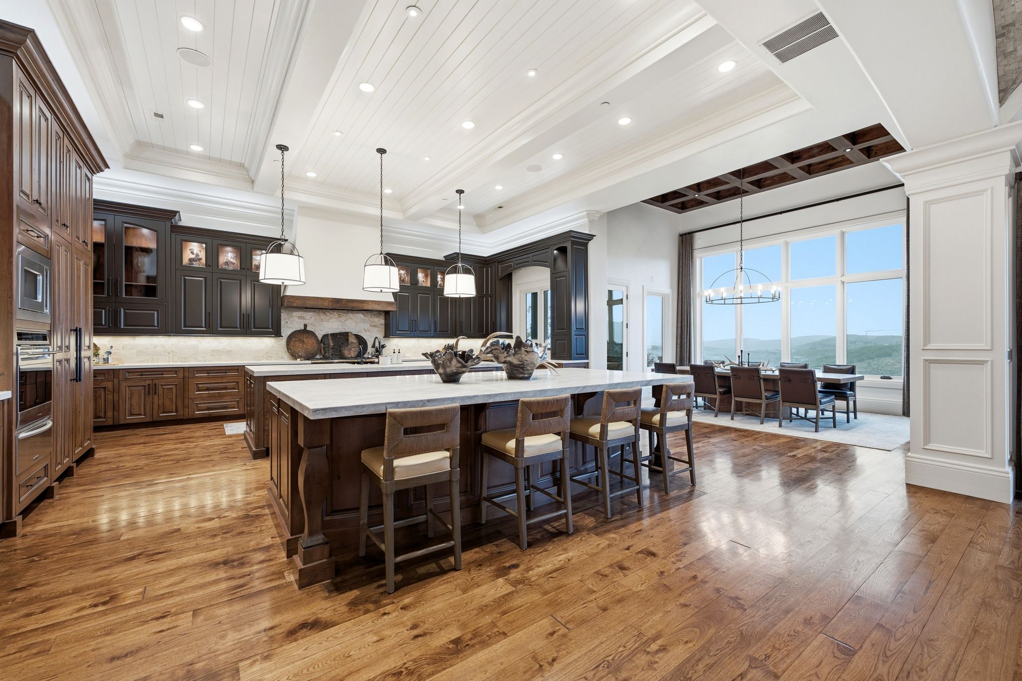 Expansive kitchen with a large central island, wood-finish flooring, and white paneled ceilings