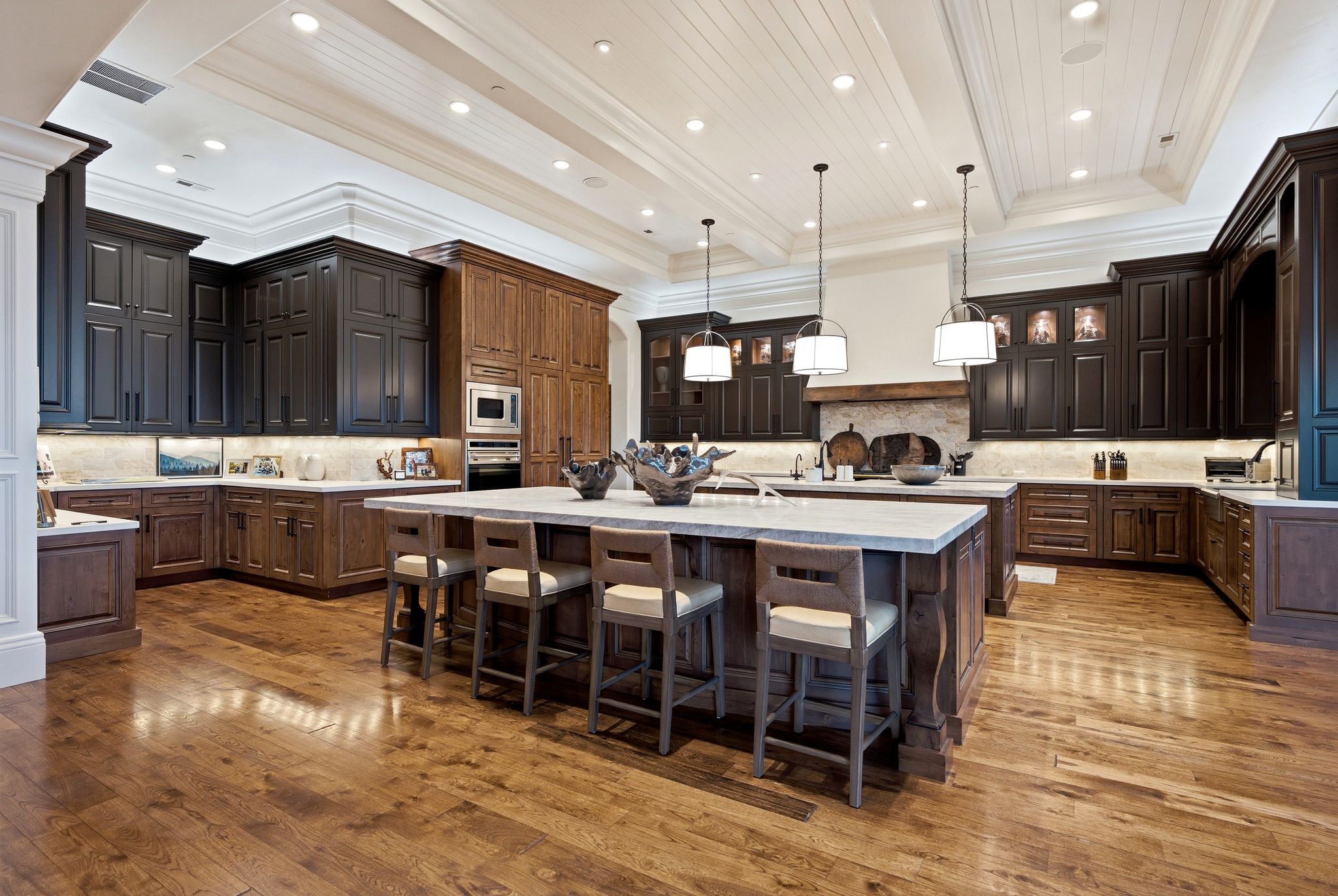 Spacious kitchen featuring an expansive center island with seating, wood-finish flooring, two-tone cabinetry, recessed lighting, and a coffered ceiling with shiplap accents