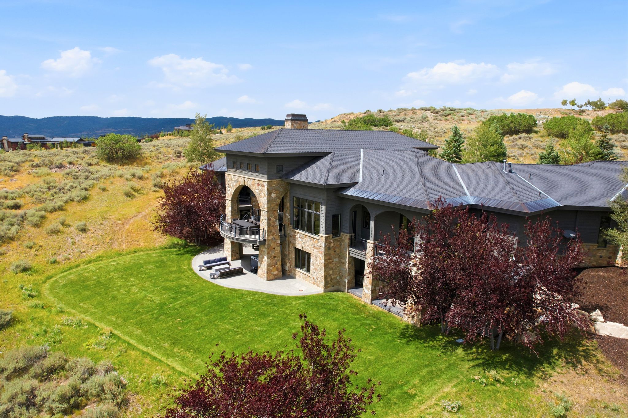 Luxury residence featuring a stone and stucco exterior, arched balcony, and a multi-level roofline
