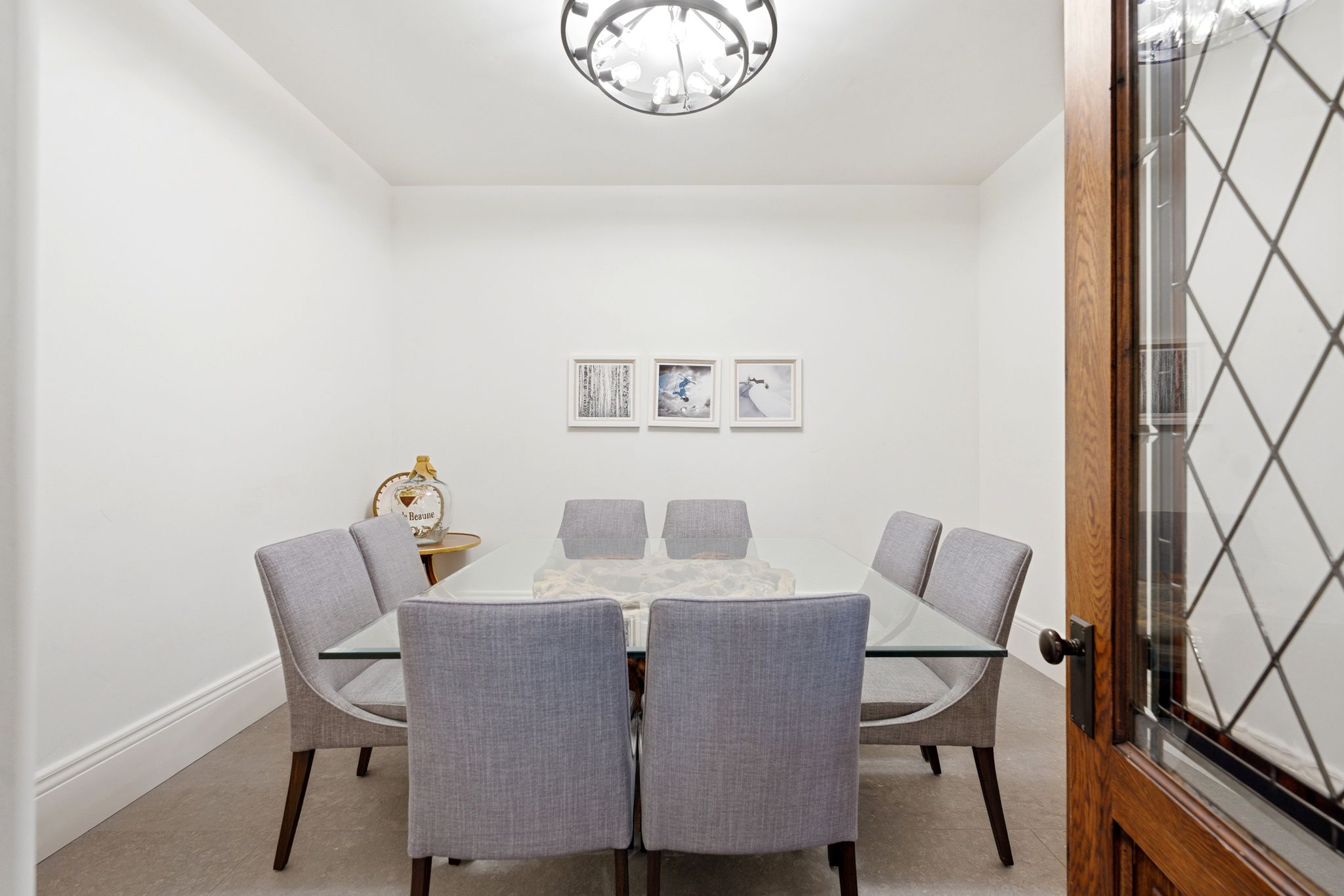 Formal room featuring a leaded glass wood door, bright white walls, and a contemporary ceiling light fixture