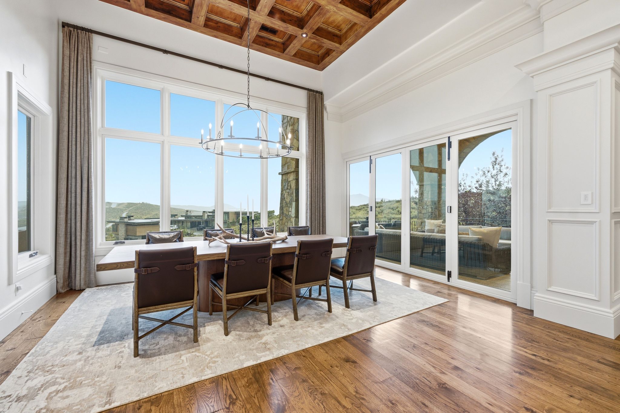 Dining space featuring a coffered wood-finish ceiling, expansive windows, glass folding doors, and wood-finish flooring