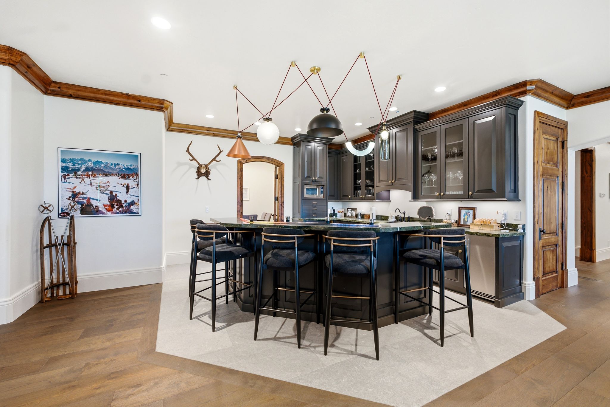 Hexagonal kitchen island with dark cabinetry, integrated mini-refrigerator, and stone countertop